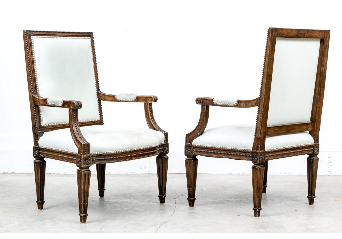 Pair of fine leather upholstered fauteuils with square shaped backrest surrounded by carved beads. Upholstered in soft neutral leather. The arms with manchettes and silver-tone nail head decorations. A string of carved beads run down the center and