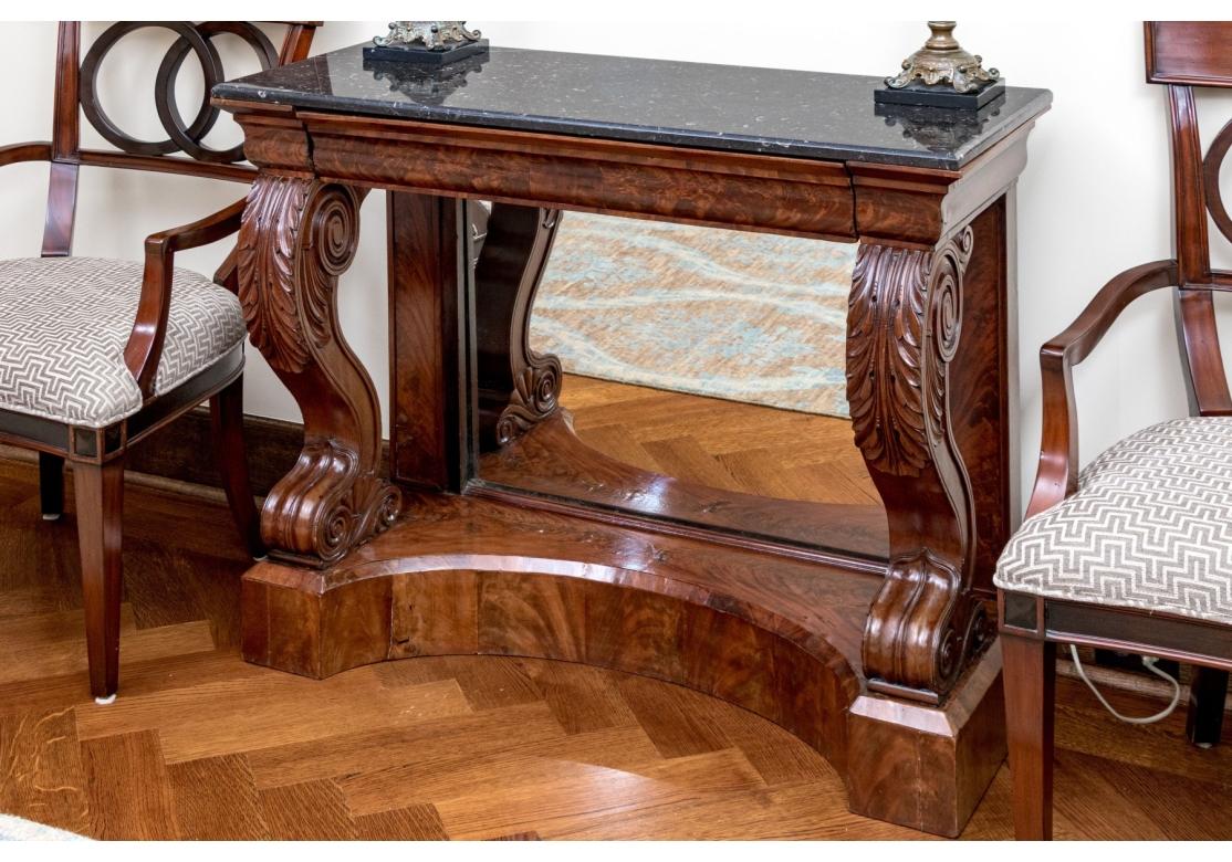 Une table ancienne de style Regency en placage rouge-brun, avec un plateau rectangulaire en pierre noire et un long tiroir le long du tablier, reposant sur des pieds cabriole à volutes avec des genoux sculptés d'acanthes et des pieds arrières droits