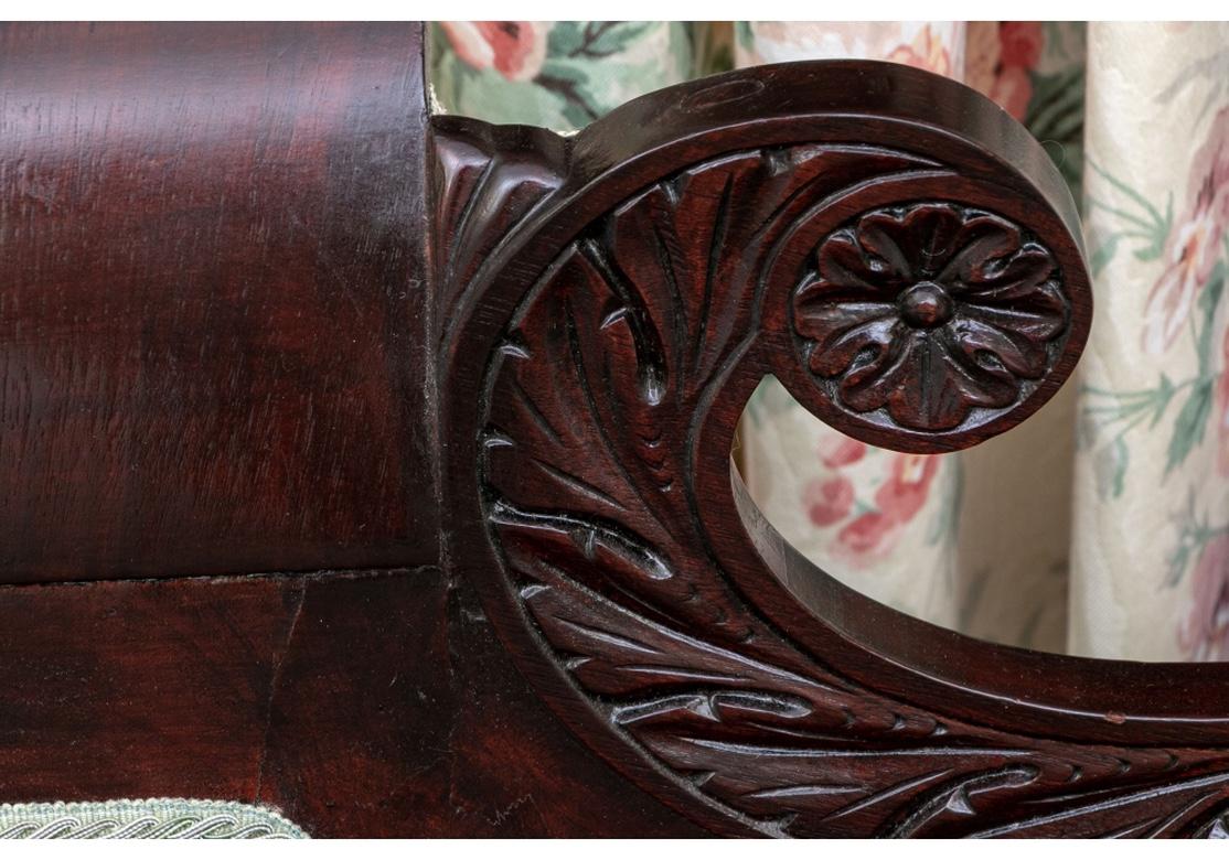 Fine American Empire sofa with striking form and masterful carving. The crest rail with carved leafy scrolled ends with center rosettes. The rolled arms with wonderful coiled scaly dolphin ends with center leafy rosettes as small pull out drawers.
