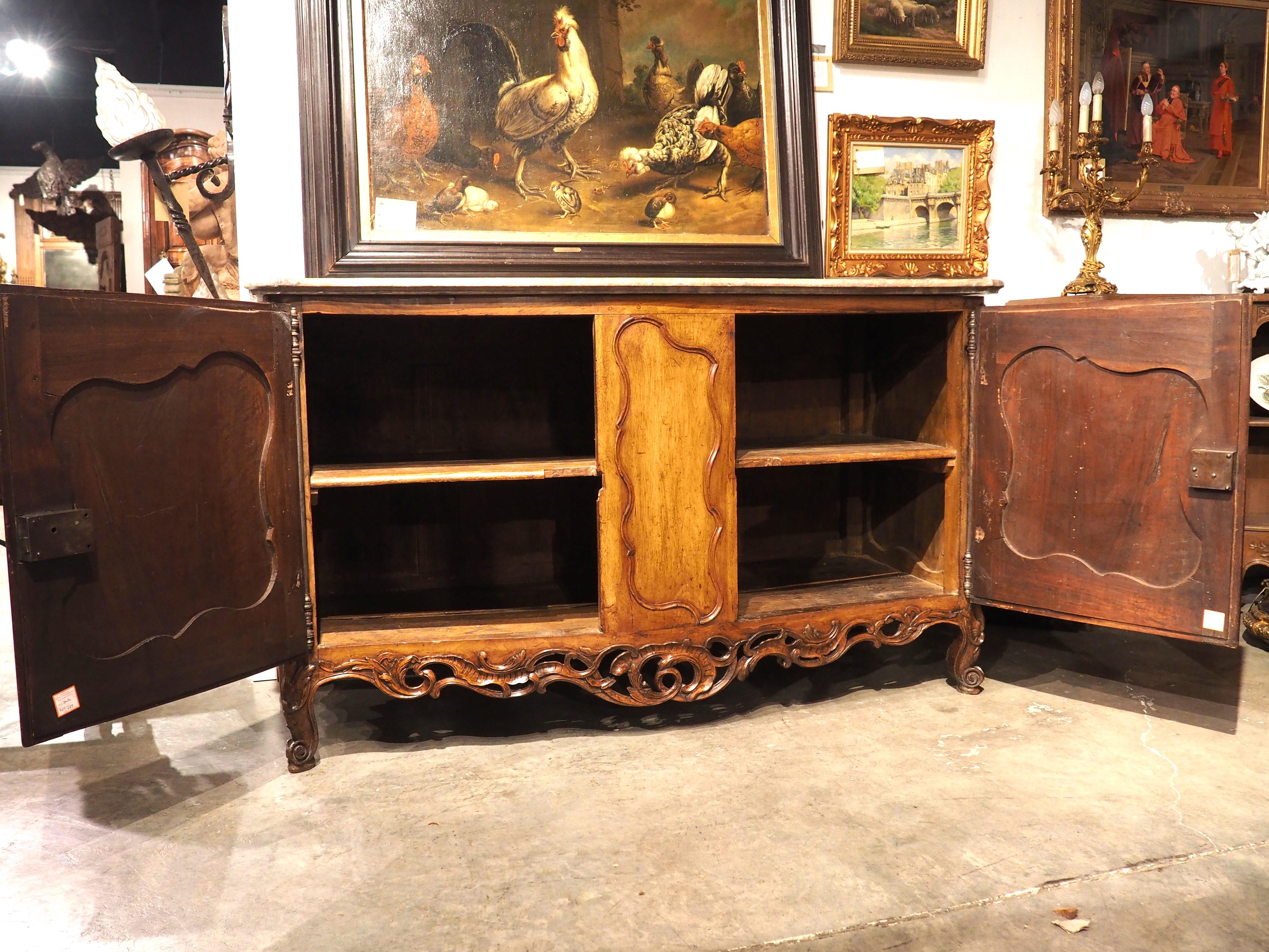 Dating to the period of Louis XV (circa 1750), this large and elegant walnut buffet de chateau was hand-carved in the Southern French town of Nimes. Woodworkers in Nimes adhered to the style dictated by the period, but these talented ebenistes added