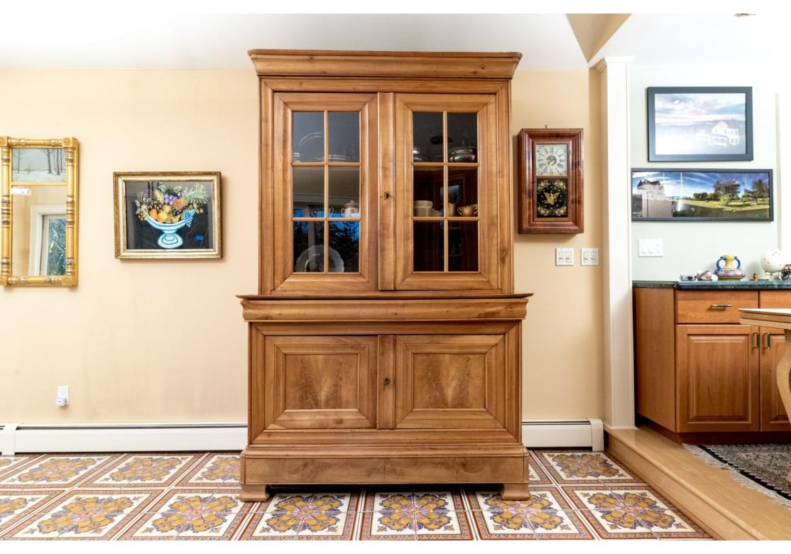 Une grande et exceptionnelle bibliothèque vitrine de style Louis Philippe en cerisier finement grainé. 
La partie supérieure est ornée d'une couronne moulée surmontant des portes vitrées à double battant s'ouvrant sur deux étagères en bois. Le corps
