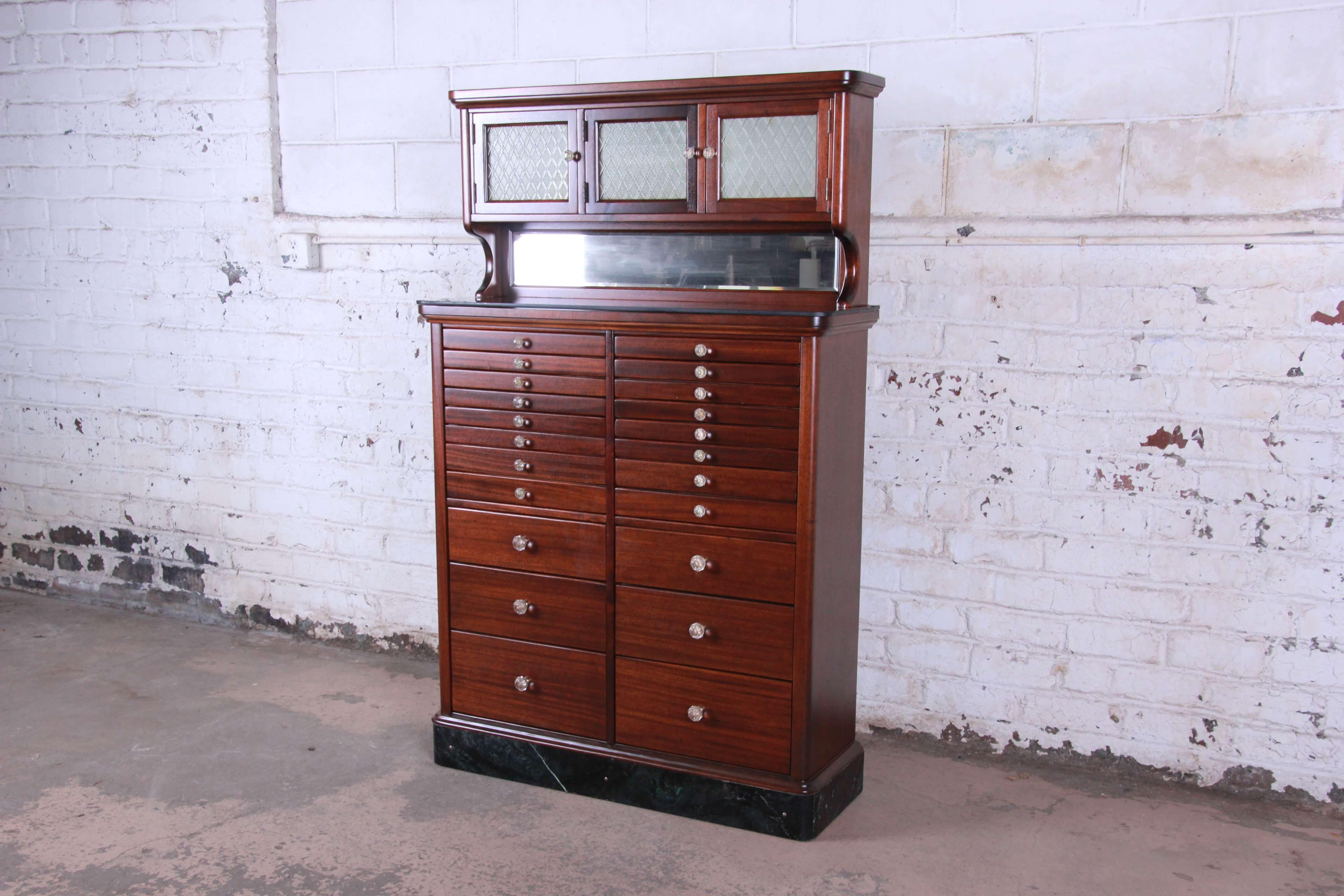 Offering a truly unique and extraordinary antique mahogany marble base dental cabinet manufactured in 1929. The piece features 22 drawers with 46 ceramic dental trays within the piece. It features a hidden locking system with a hidden level in a