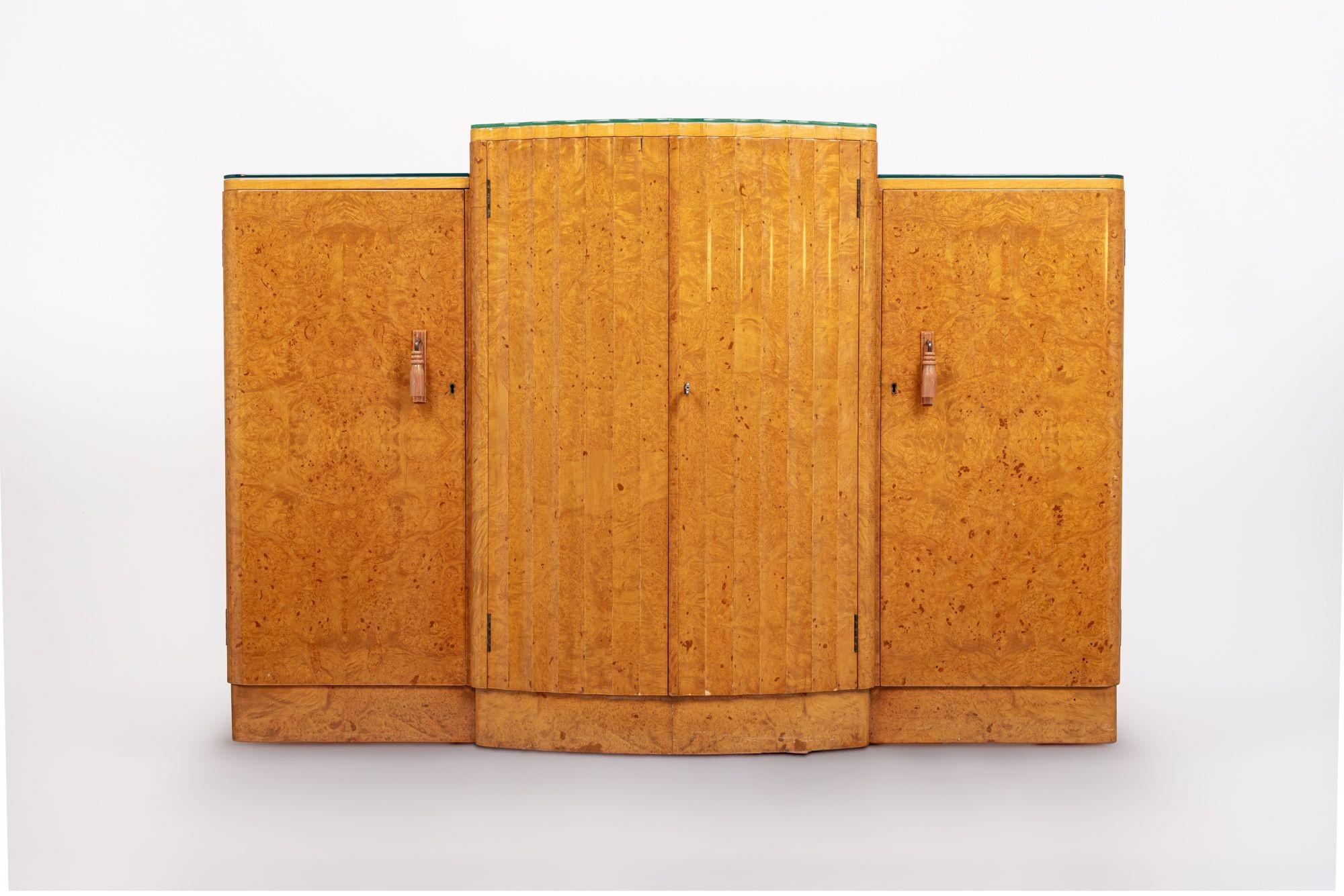 This exquisite English Art Deco maple wood bar cabinet or sideboard is attributed to Harry & Lou Epstein and is circa 1930. The cabinet is expertly handcrafted and features stunning birdseye maple and a “skyscraper” breakfront design with a taller