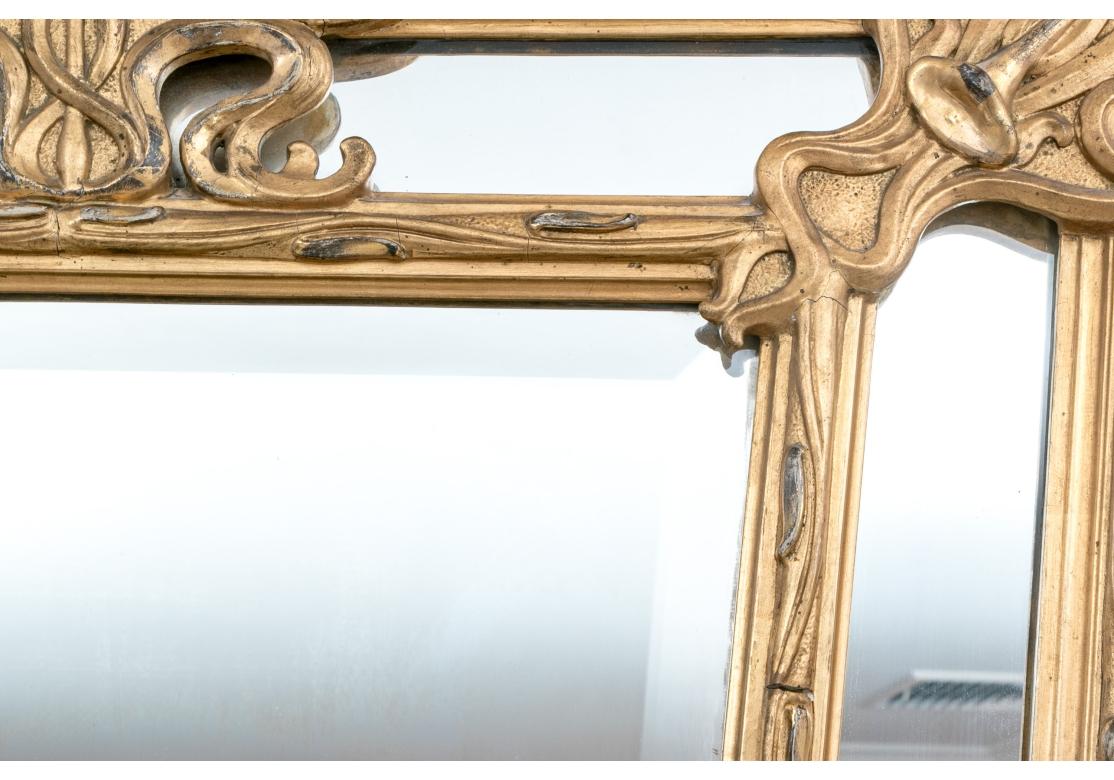 A intricate and very decorative gilt wood and gesso openwork framed mirror. floral motifs throughout the frame with a beveled edge mirror within. The Mirror features the fine rhythmic sinuous curves and flowers Associated with the Art Nouveau style.