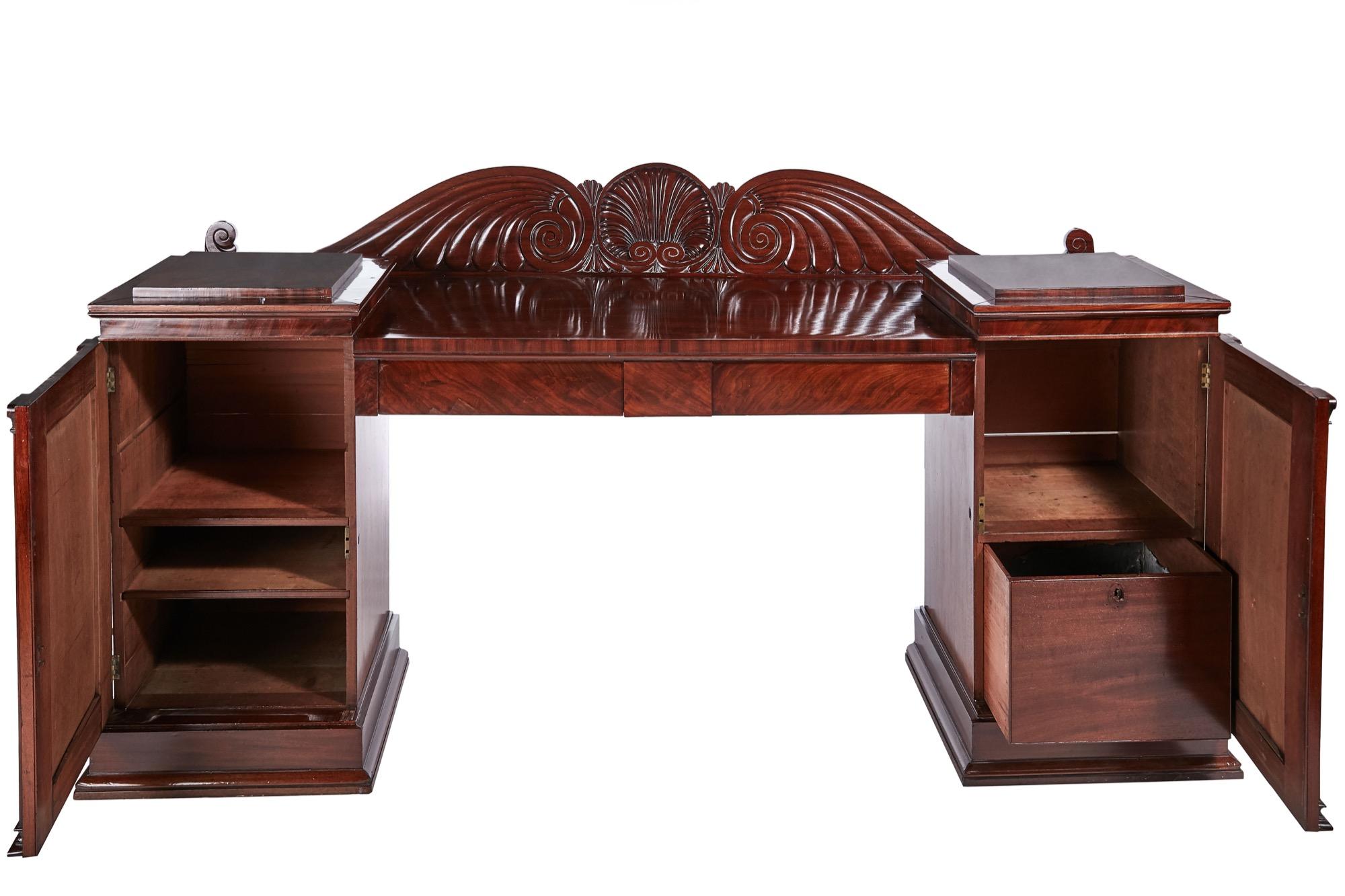 This is an outstanding quality 19th century antique mahogany carved sideboard with an exquisitely carved shaped back and two drawers to the frieze. It is supported by two pedestals with striking flame mahogany doors and a fitted interior. It stands