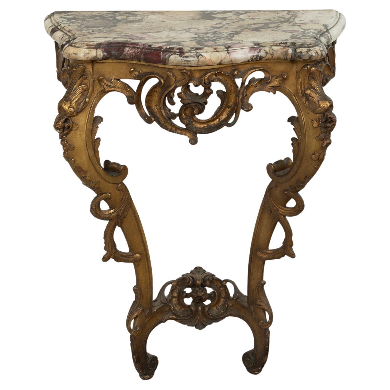 This exceptional 18th-century antique Rococo-style gilded console table from France is a stunning testament to opulent craftsmanship. 
Featuring an intricately carved wooden base with a radiant gilded finish, its flowing curves and ornate floral