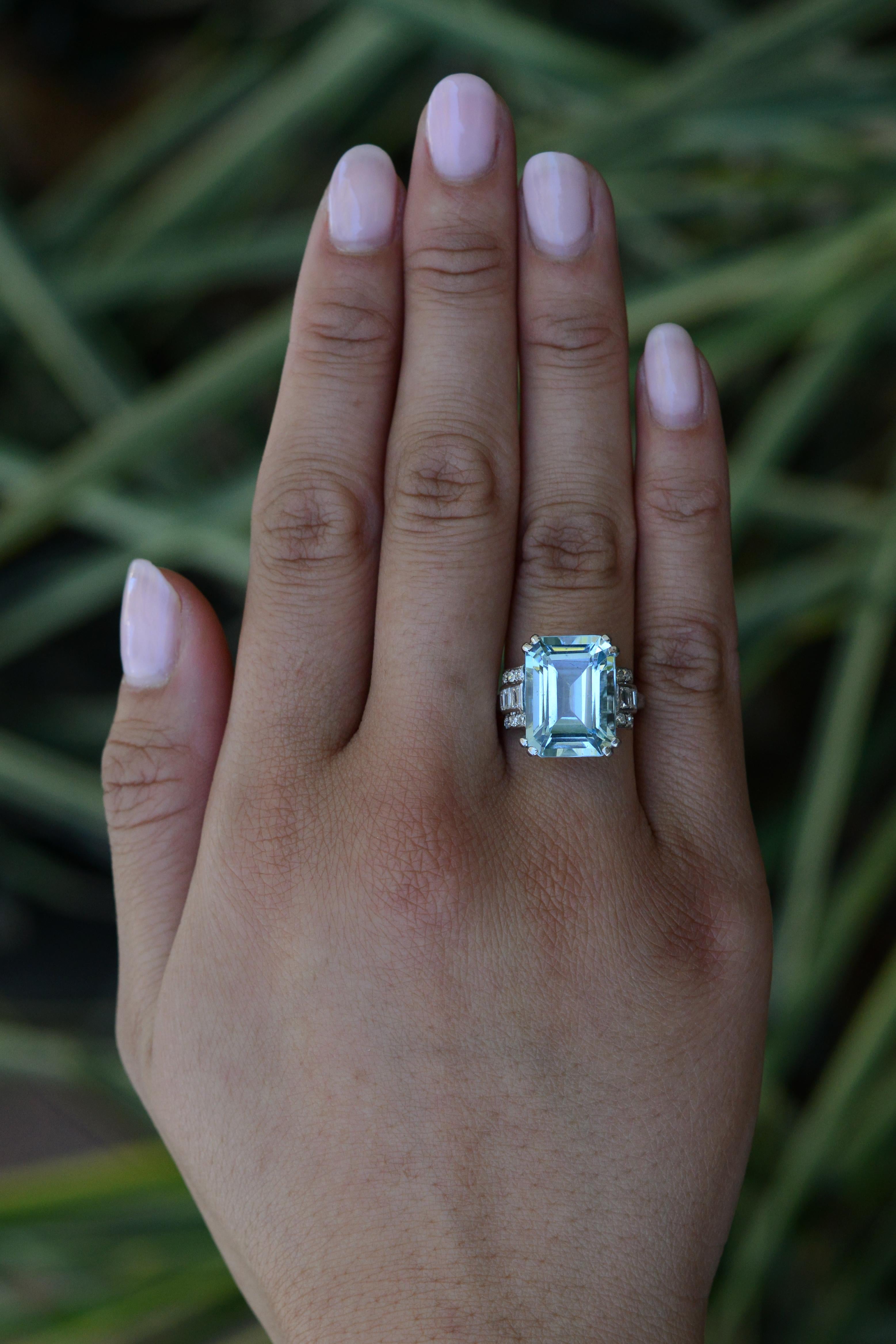 A perfect example of linear Art Deco design, this large and impressive 11.54 carat aquamarine cocktail ring makes a bold statement. The sleek streamlined staircase platinum setting is adorned with a 1/2 carat of scintillating near colorless diamonds
