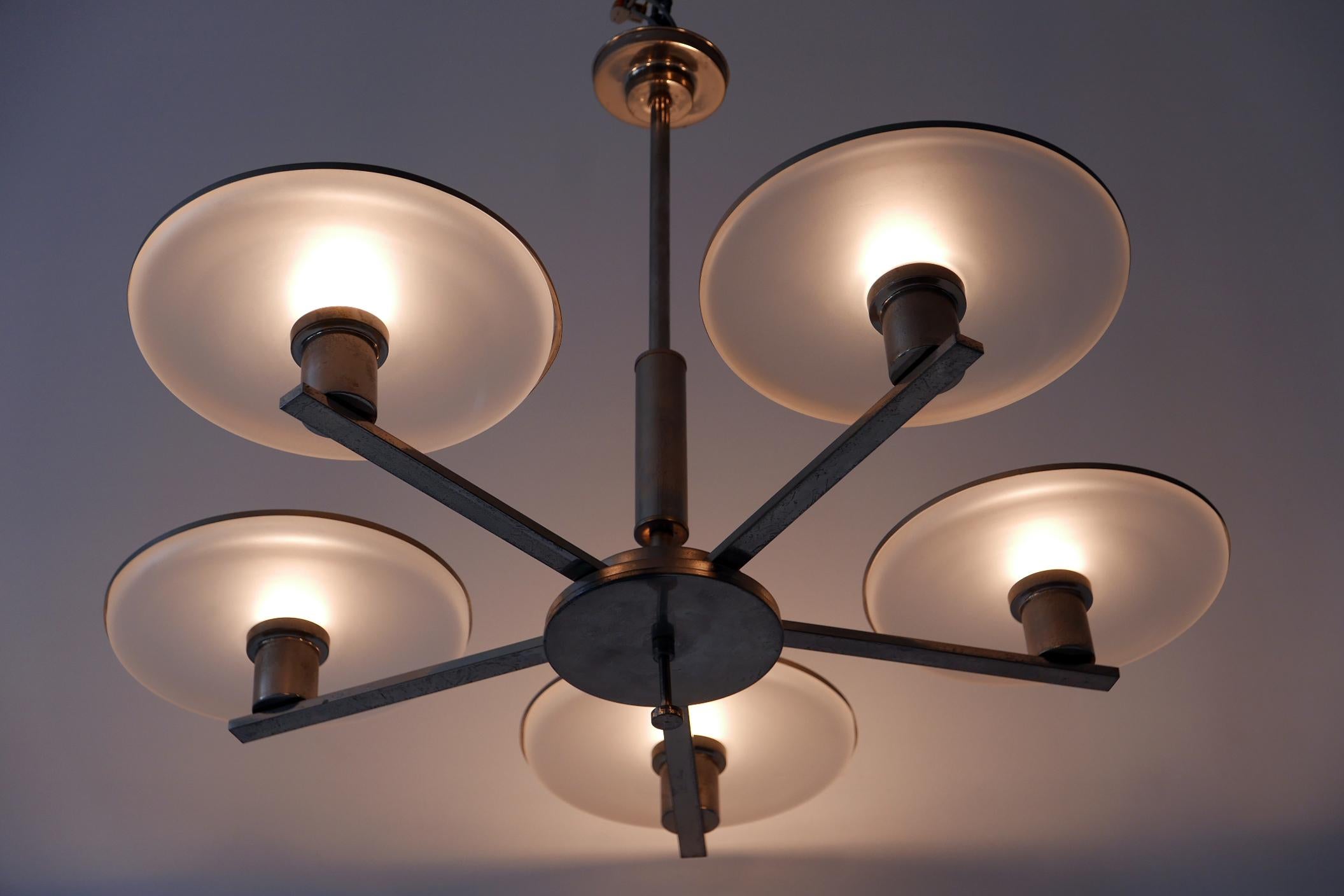 Magnifique et minimaliste lustre / lampe suspendue à cinq bras de style Bauhaus / Art déco. Conçue et fabriquée dans les années 1930, en Allemagne. 

Réalisé en laiton nickelé et en verre, le lustre nécessite 5 ampoules à vis Edison E27 / E26. Il