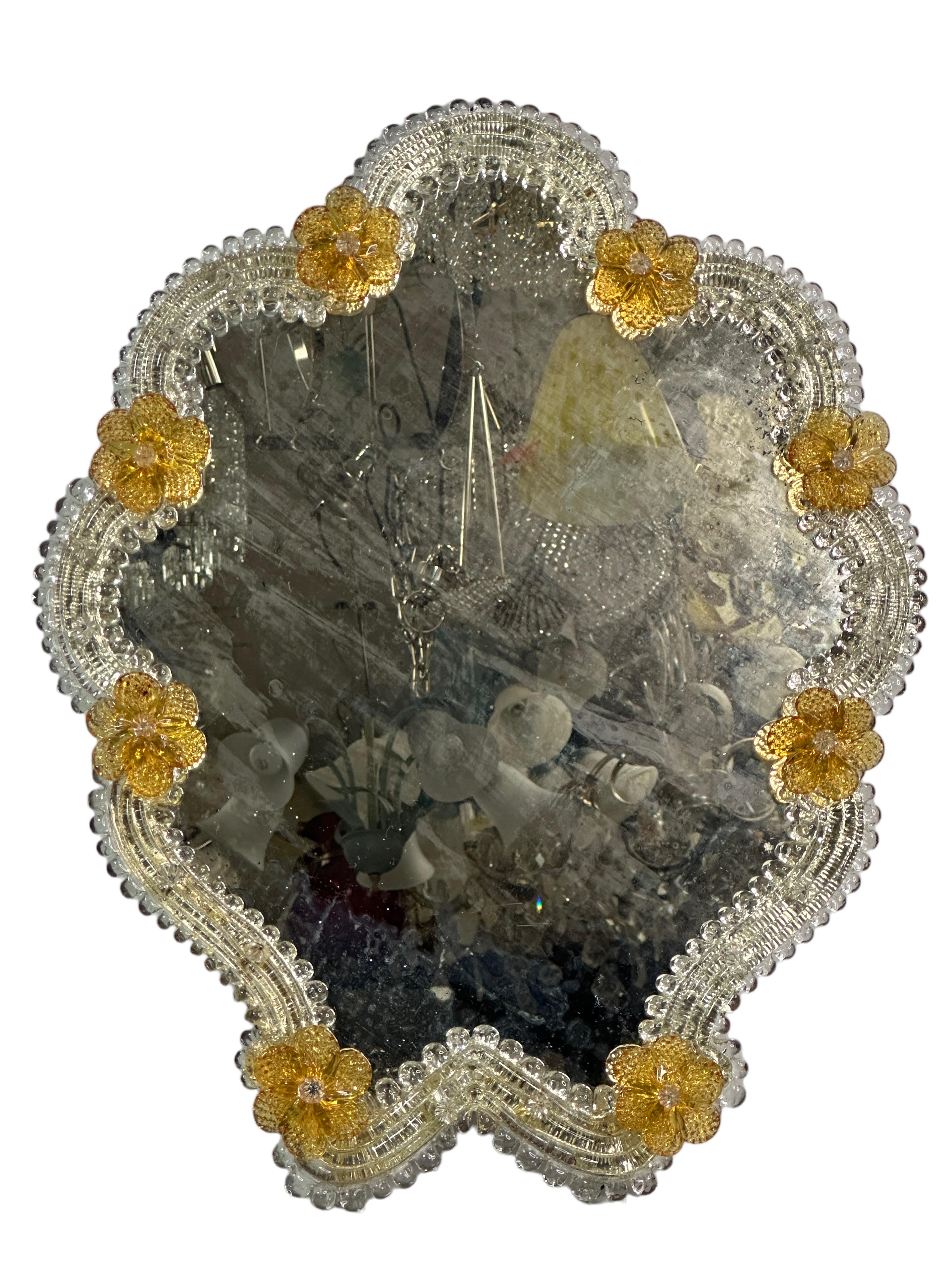 A stunning medium Murano glass mirror surrounded with handmade amber smoked glass flowers. Age approx. 1930s or older. Some blind spots and distressed parts in the mirror but this is old-age. With signs of wear as expected with age and use.