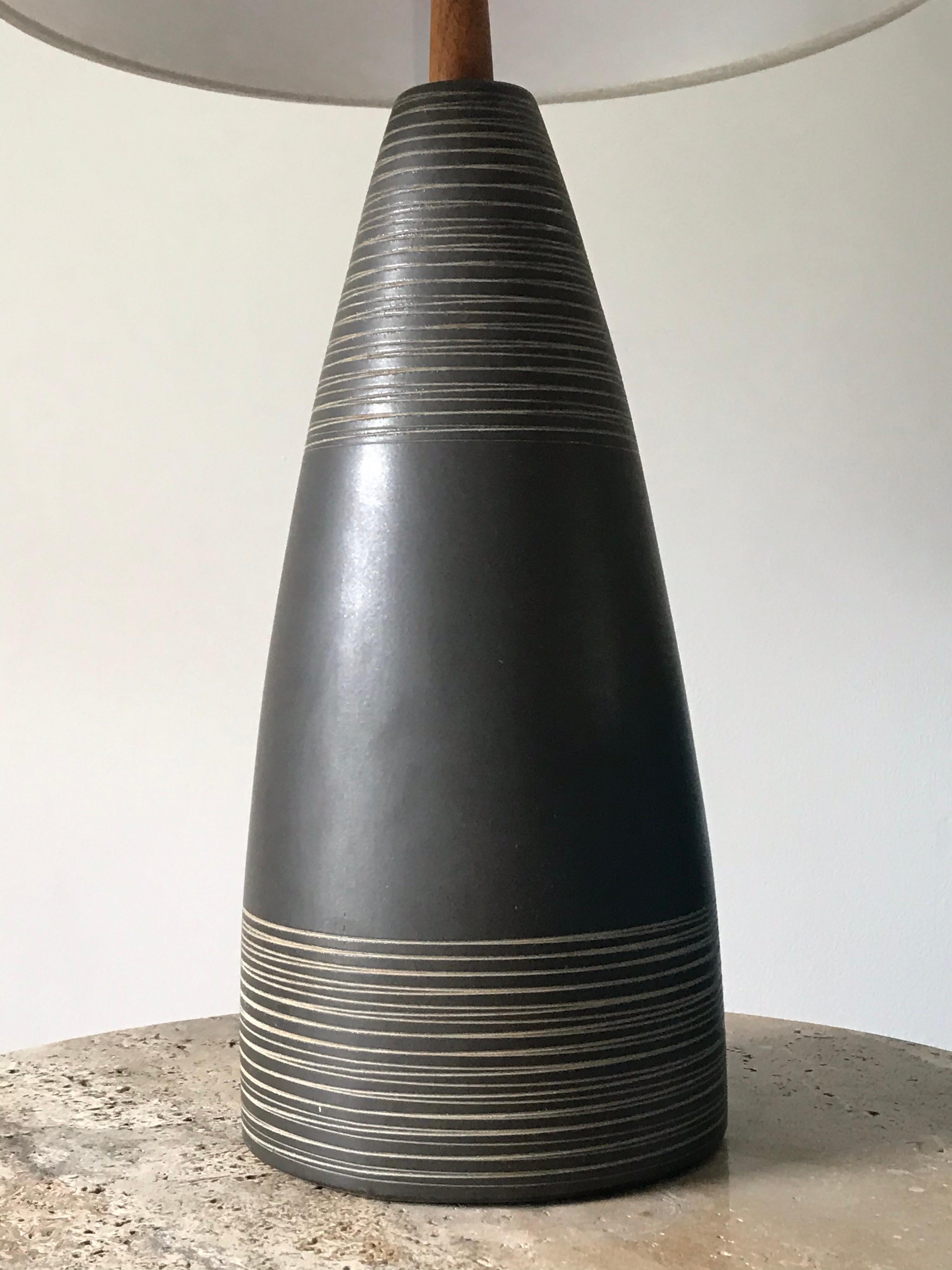 Beautiful dark grey ceramic table lamp by famed ceramicists duo Jane and Gordon Martz for Marshall Studious. Incised detail around the top and bottom with a matte finish. Finial has been replaced, newer wiring, and new shade. 

Measures: Ceramic
