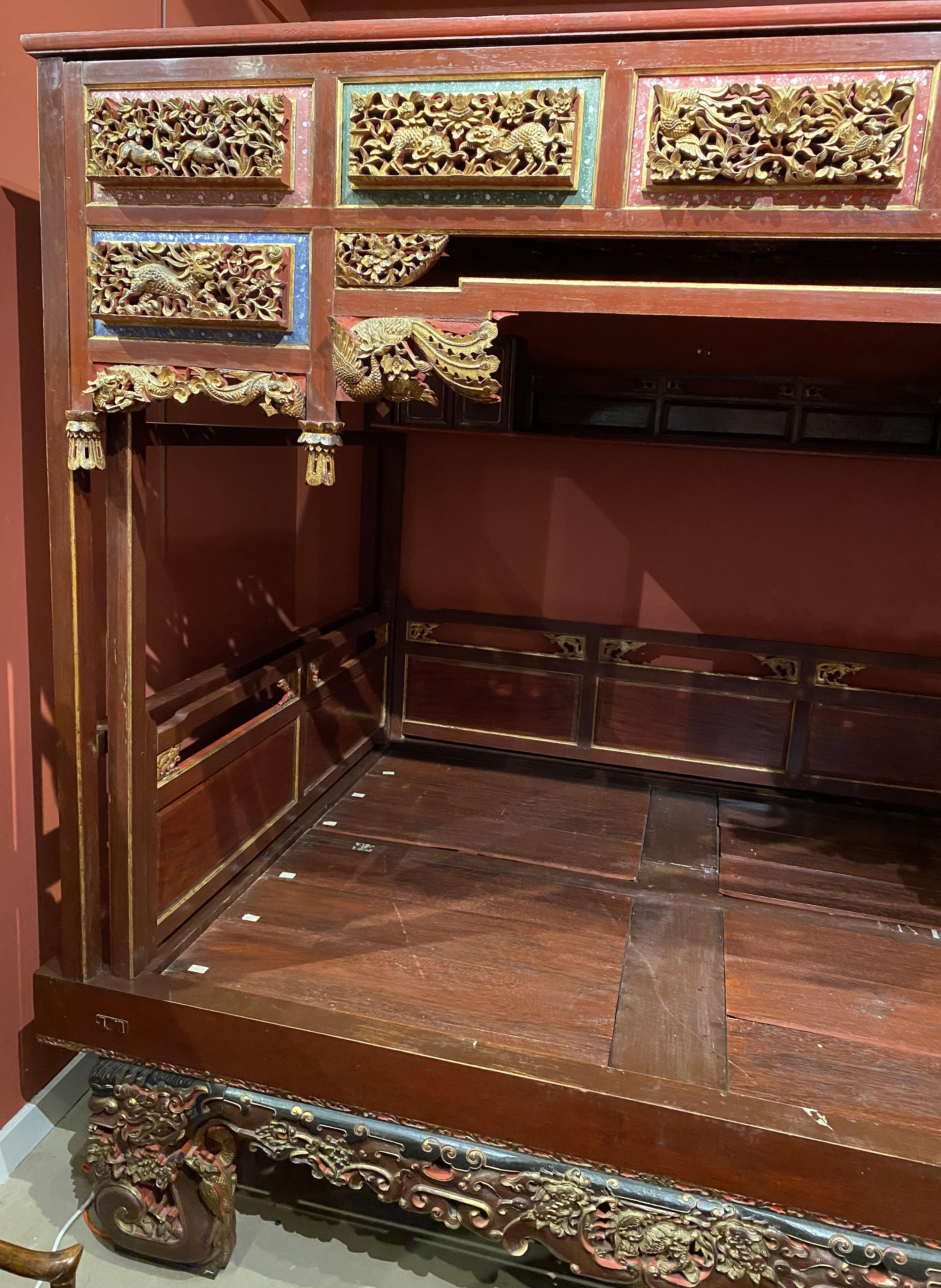 An impressive Chinese canopy wedding bed with pierce carved polychrome and gilt panels and supports featuring dragons, deer, peacocks, serpents, and other animals, as well as vines and flowers surrounding a  sleeping platform that will accommodate a