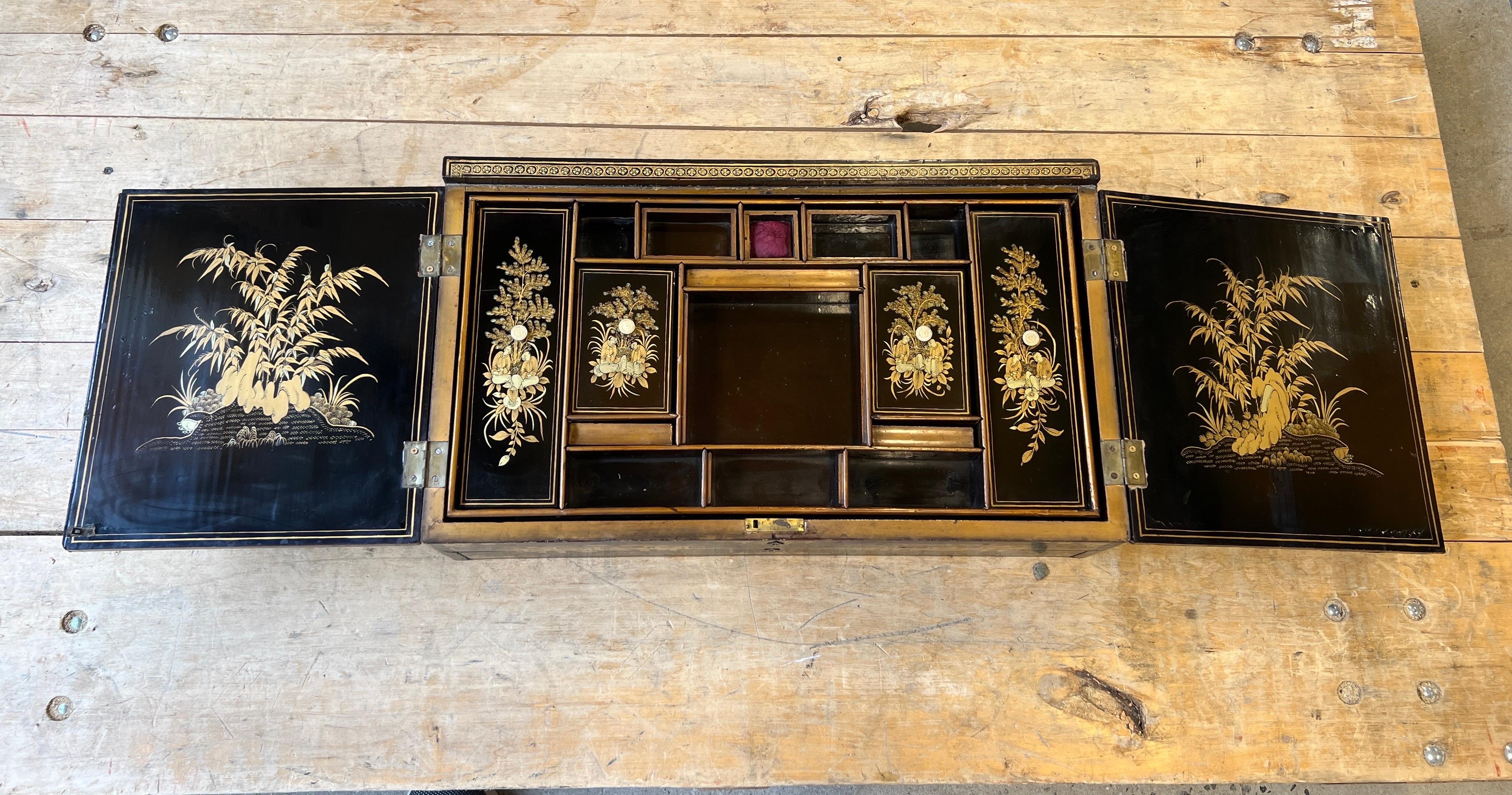 Chinese export, circa 1820.
An exceptional quality and rare form. Featuring figural landscape decorations in gilt to the main black lacquer doors, which open to reveal 13 separated compartment boxes on one removable tray with an open area