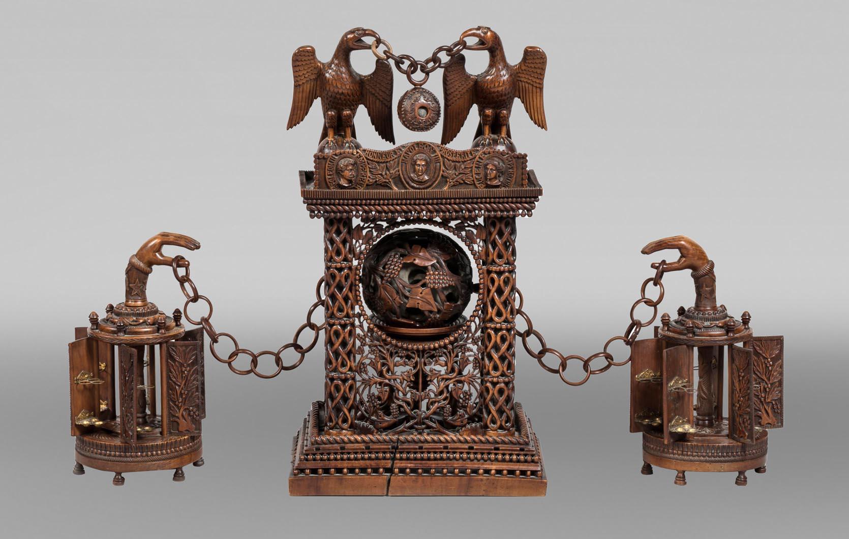 A stunning cigar humidor made of finely carved wood, stained to resemble mahogany, composed of three distinct elements with exceptional refinement.

At its center, an architectural structure with four openwork columns houses a Canton sphere resting