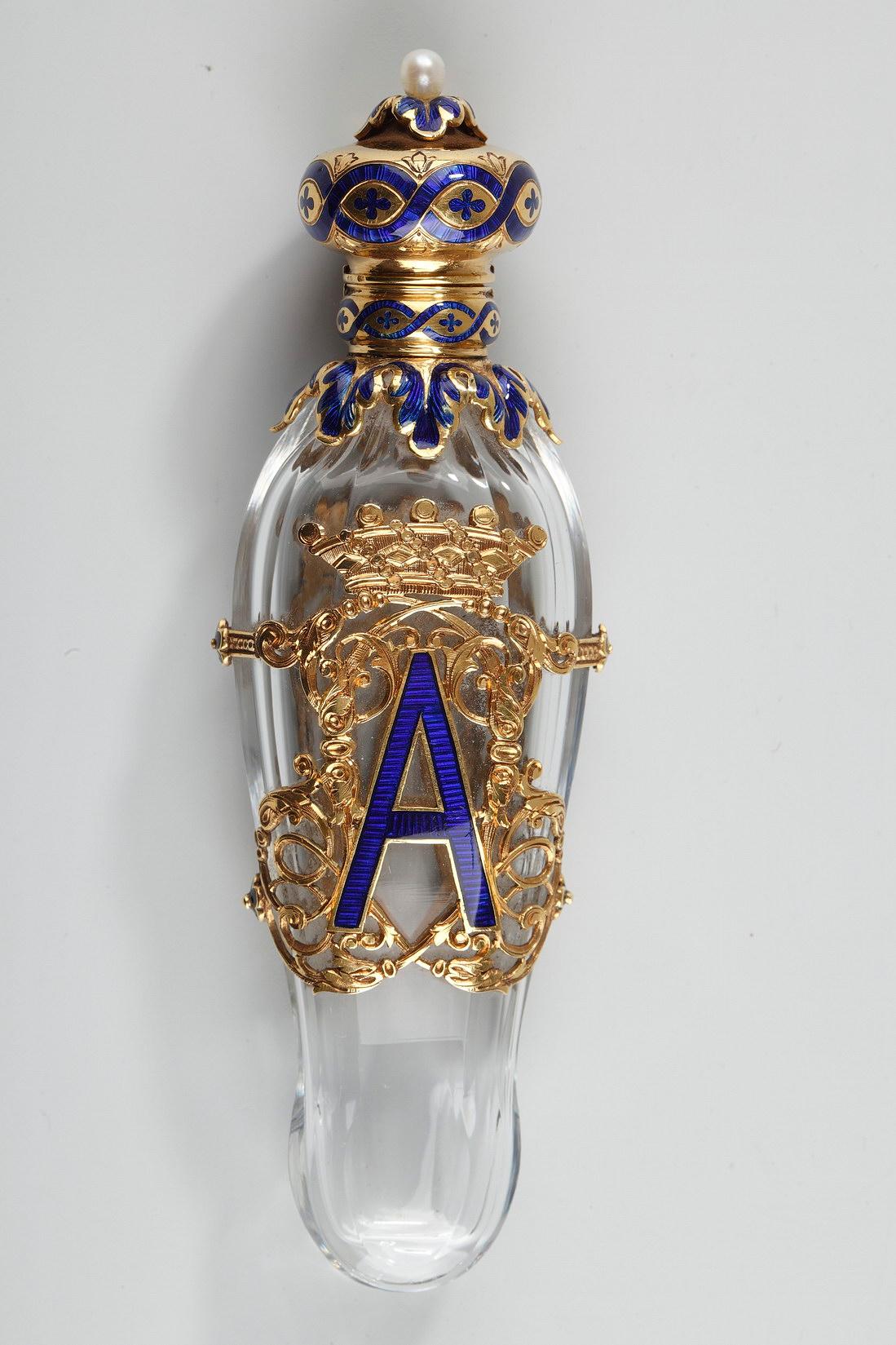 Exceptional conical flask made of faceted crystal. The flask is set in an openwork mount made of gold and royal blue enamel and intricately sculpted with scrollwork motifs. A large monogram letter A is at the center of the mounting. The monogram is