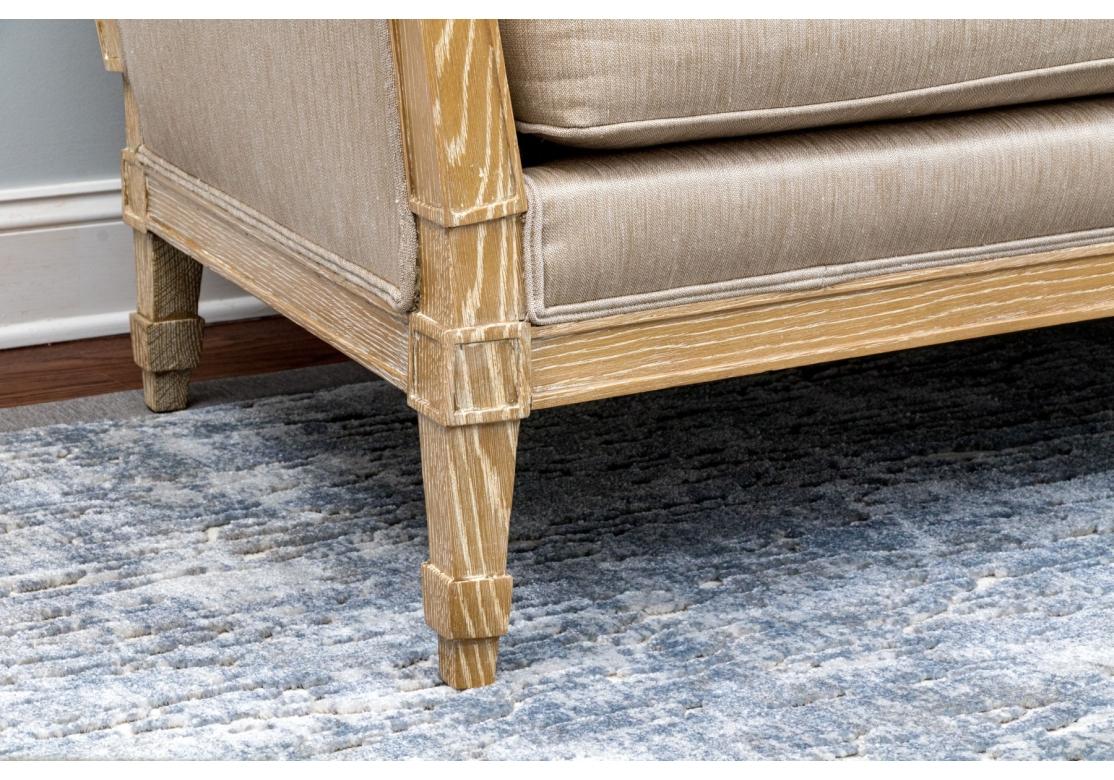 Un beau canapé dont le design contemporain s'inspire du style Directoire français emblématique. Impeccablement rembourré dans un tissu tissé taupe naturel et encadré dans un chêne cérusé saisissant. Le haut dossier et les accoudoirs confèrent un