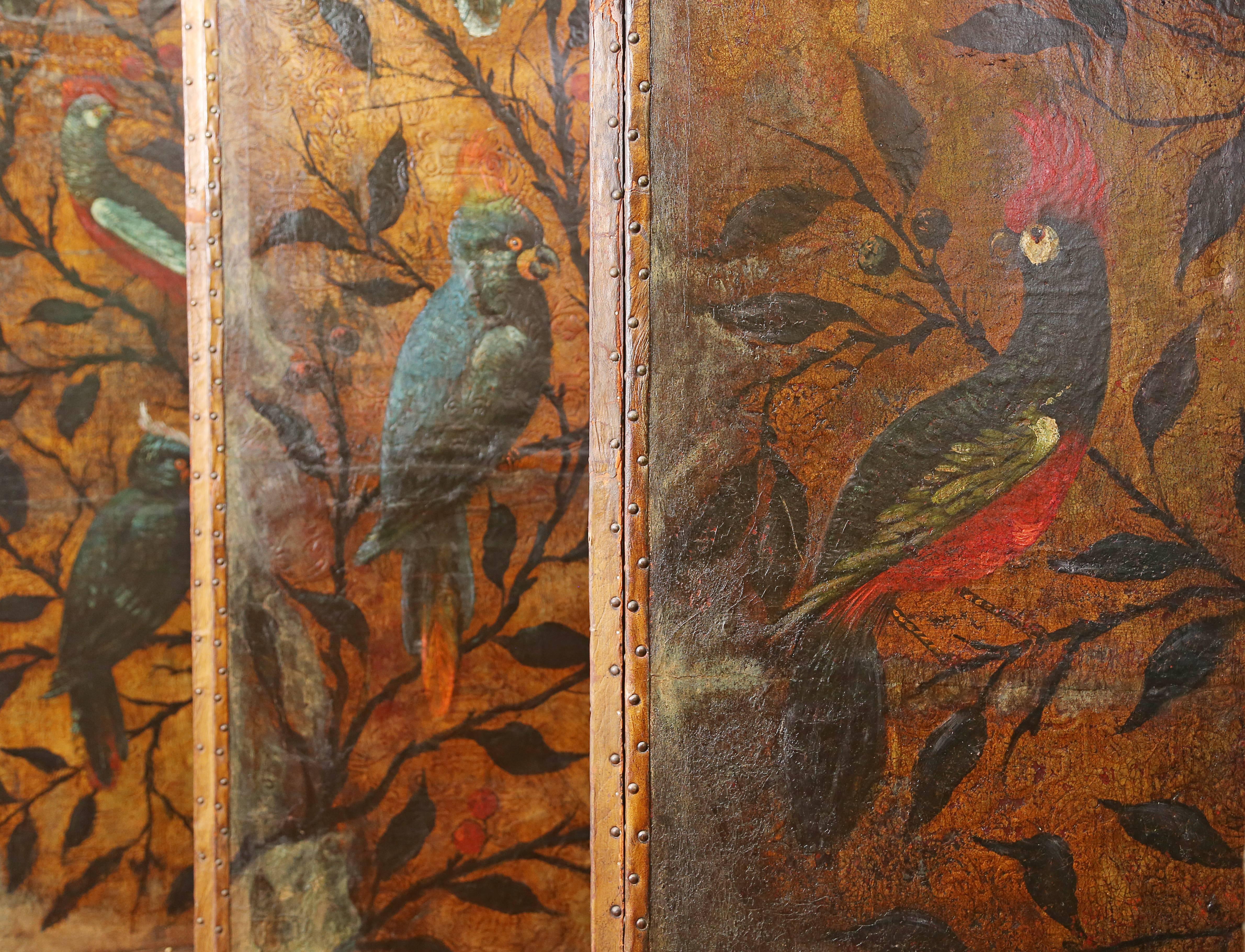 Each with four panels vibrantly painted with parrots and other tropical birds perched on tree boughs on a gilt and foliate-embossed ground. Photograph has screens arranged as if one long continuous screen. Each panel measures 24