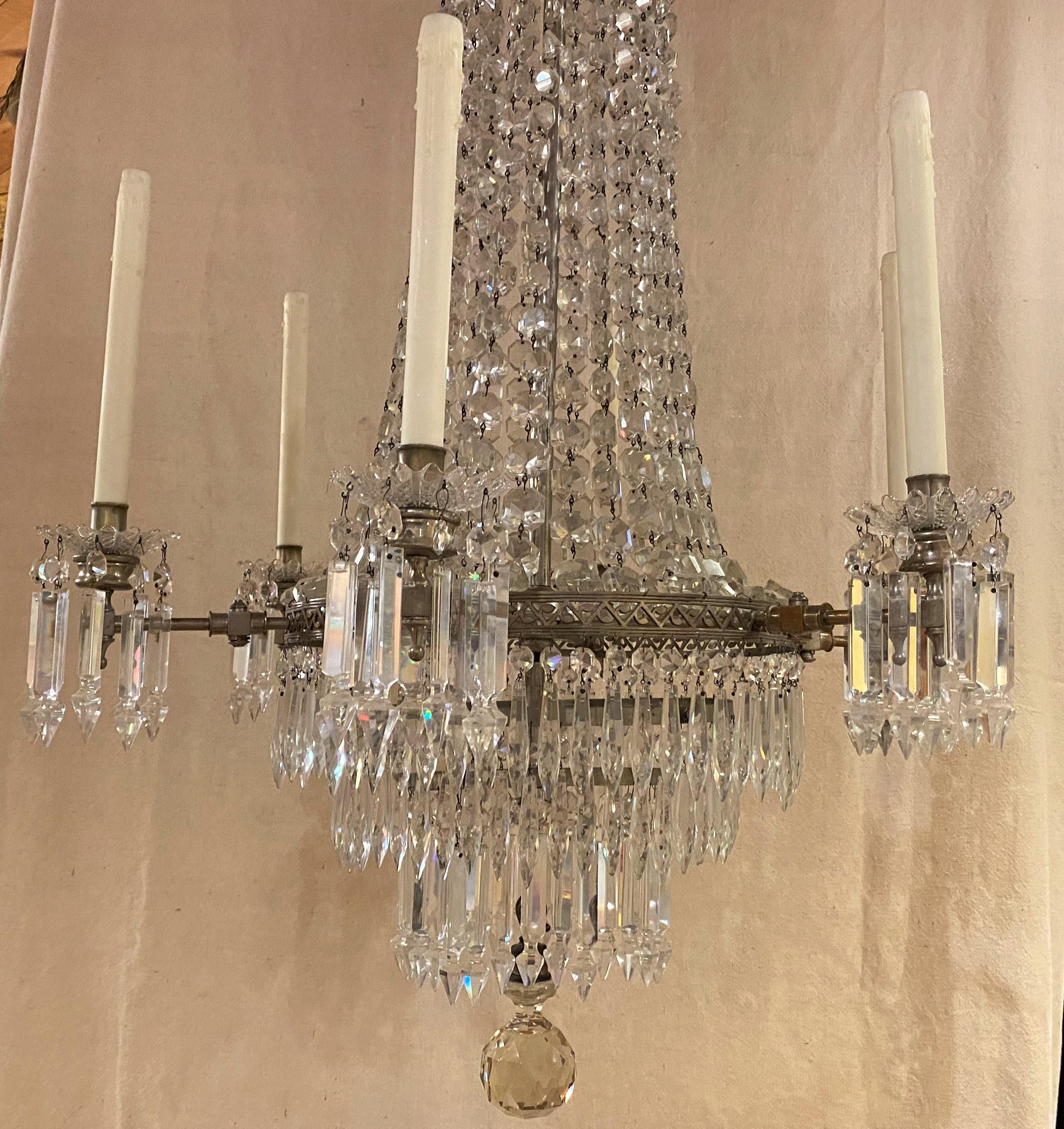 An exceptional form six light gasolier or chandelier, originally fitted for gas with tubes present, electrified, and ornamented with a fountain form of descending layers of crystal prisms, each light has a crystal foliate form bobeche with a ring of