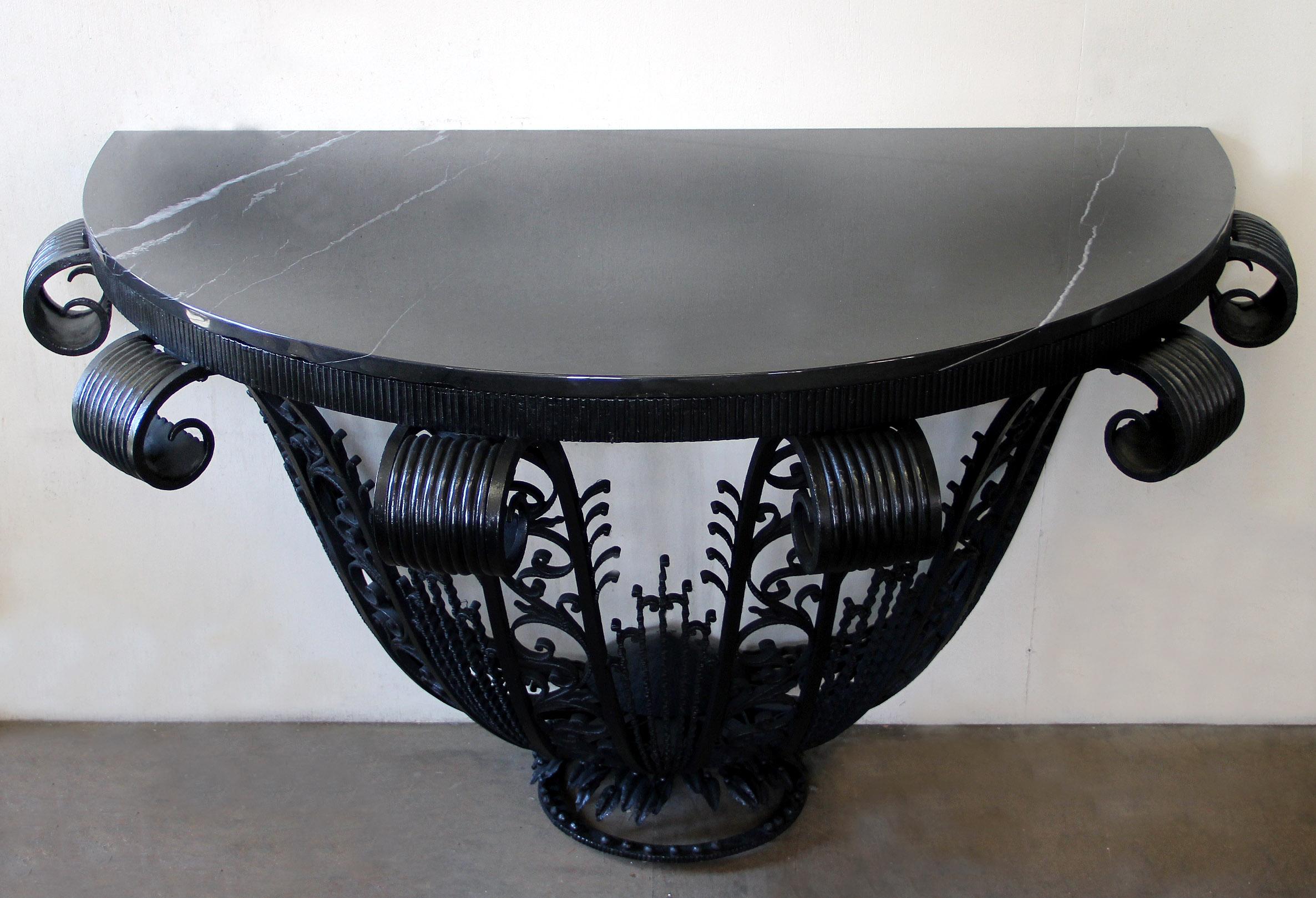 An exceptional early 20th century wrought iron marble-top Art Deco console

The demilune shaped black marble top above foliage designed iron legs, standing on a circular base.

In the manner of Edgar Brandt.

Edgar Brandt (1880-1960) was a