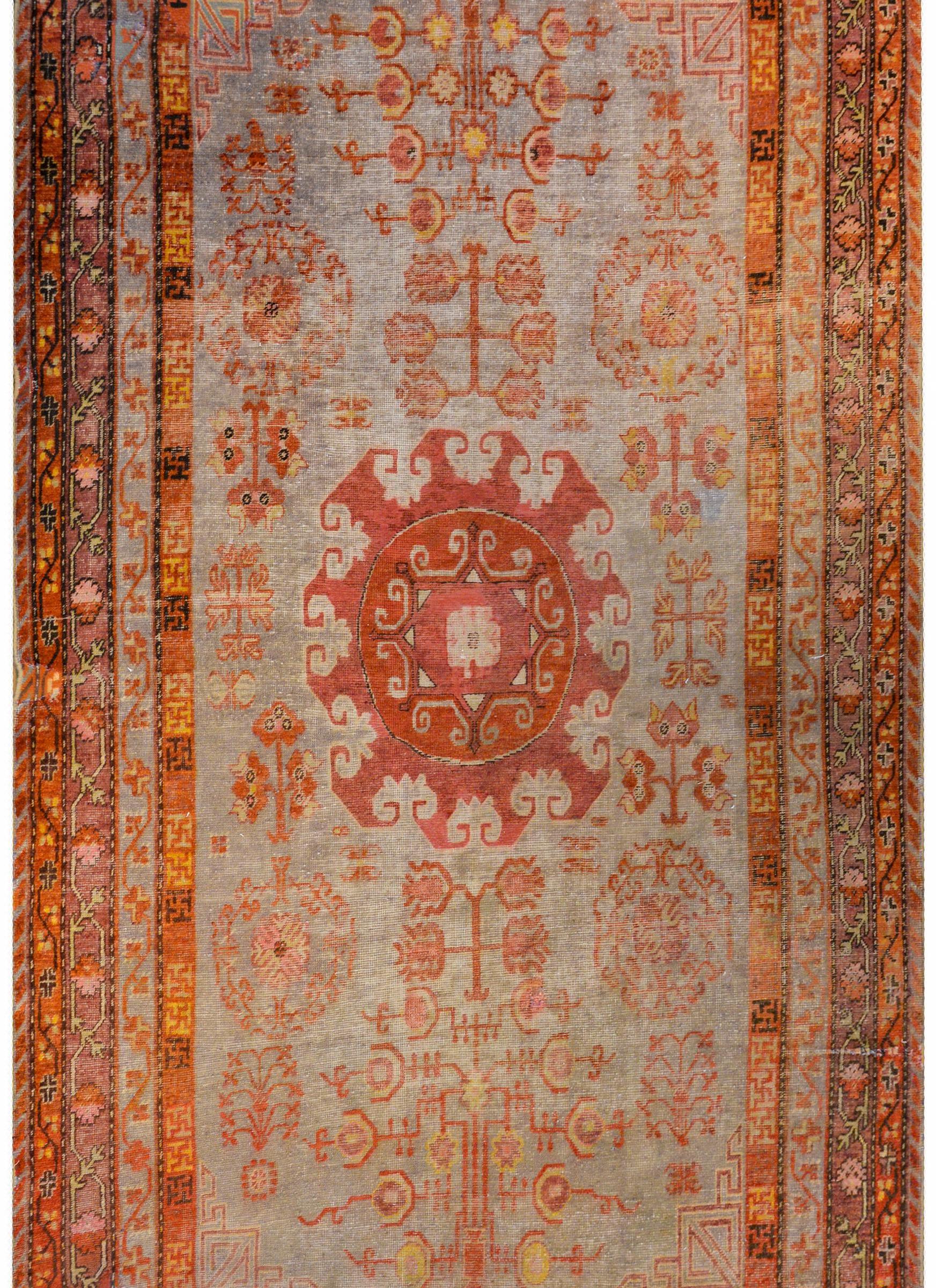 An exceptional early 20th century Central Asian Samarghand rug with a wonderful large stylized floral central medallion woven in crimson and fuchsia amidst a field of flowers and trees-of-life all woven in pale crimson, fuchsia, gold, and white on a