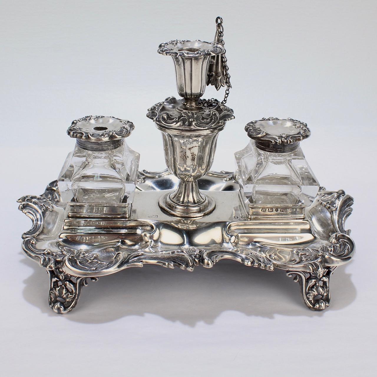 A rare Early Victorian sterling silver inkstand or standish by Henry Wilkinson.

Retaining its original bottles, lids, taper stick, snuffer and a quill or wafer compartment. The body has pierced feet and elaborate swags to the edges and borders