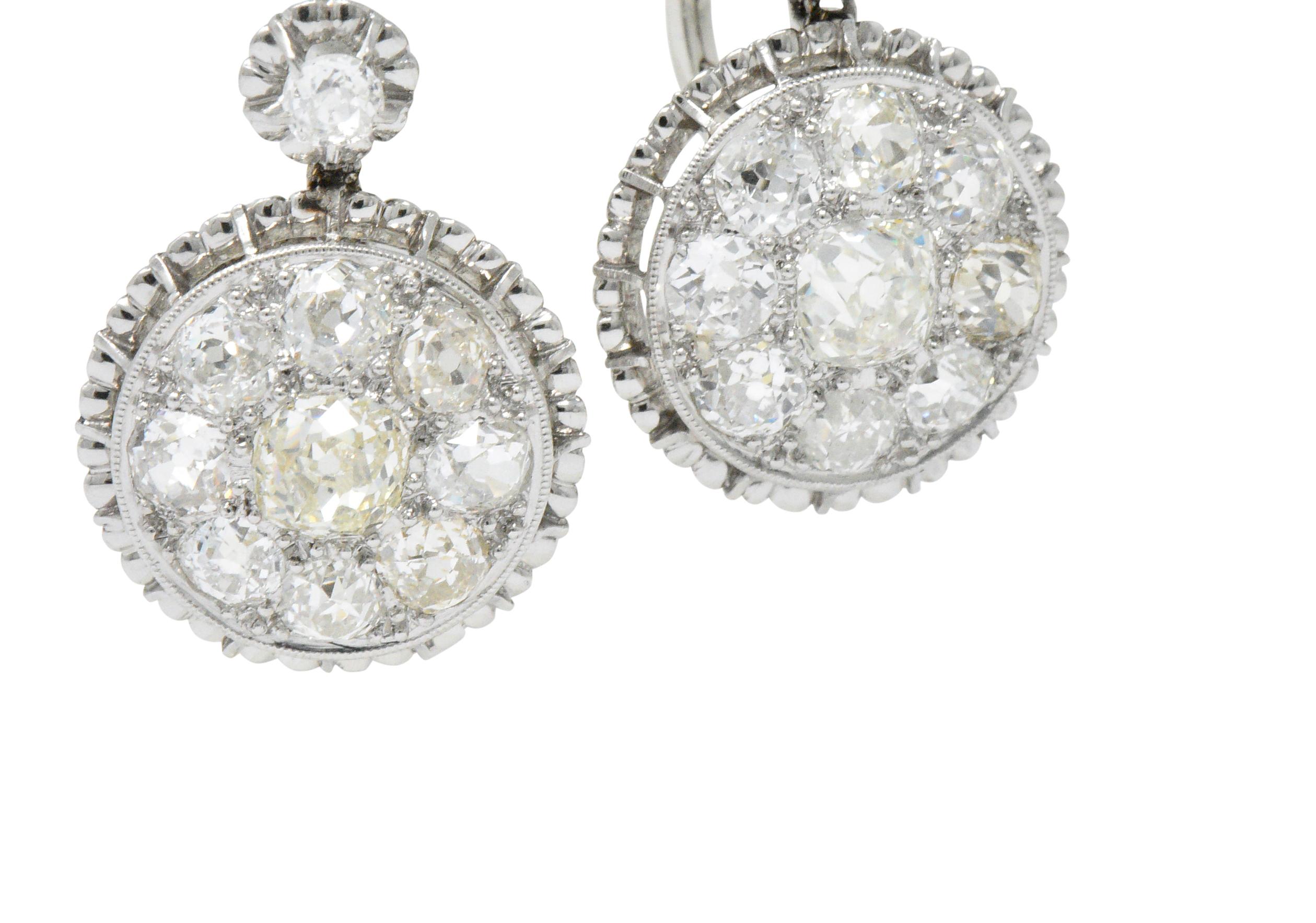Featuring diamond surmount with suspended articulated diamond cluster

Set with old mine cut diamonds weighing approximately 4.09 carats total, I to M color and VS to SI2 clarity 

Pierced, scalloped platinum frames

With 14 karat white gold lever