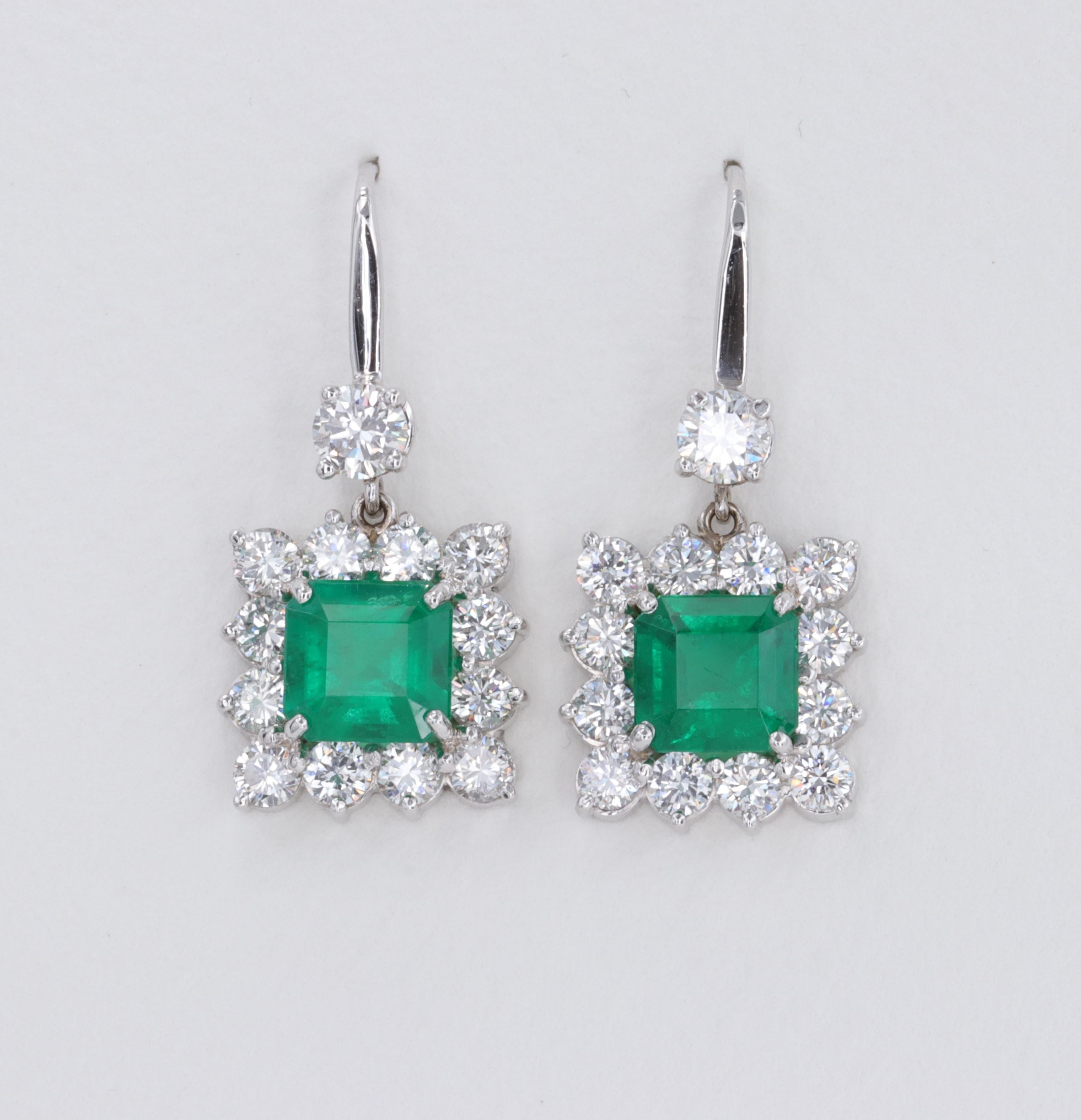 Exceptional Emerald and Diamond Halo Dangle Earrings Set in 18 Karat White Gold 

Emeralds:

Shape - Square Emerald Cut 
Weight - 2 Stones = 3.56 carats
Color - Vivid Green 
Clarity - Eye Clean

Diamonds:

Shape - Round Brilliant Cut 
Weight - 26