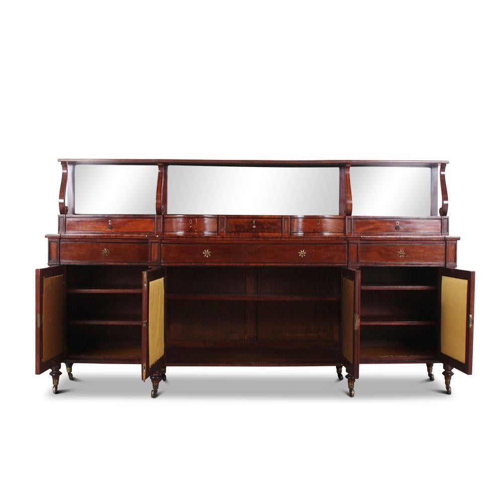 A superb English Regency period breakfront sideboard in figured Cuban mahogany having four doors below three drawers, all with ebony trimmed edges, the doors with gilt diamond pattern mesh panels. The top features ebony inlay and a set-back
