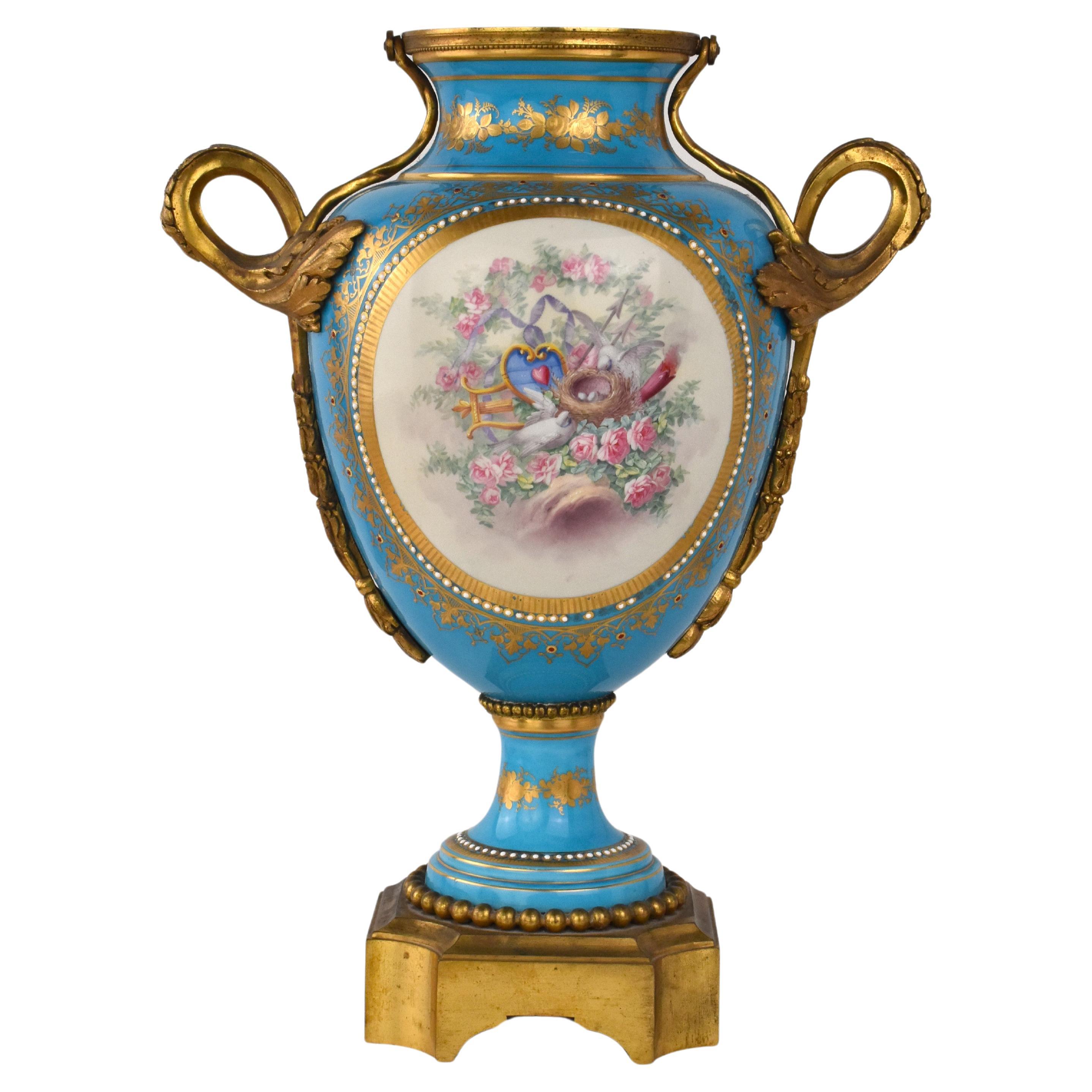 Un imponente vaso in porcellana dipinta con montatura in ormolu del XIX secolo.

forma a balaustro di colore azzurro con al centro una scena dipinta a mano raffigurante una donna, un giovane uomo e due angoli. Il retro presenta una scena di uccelli