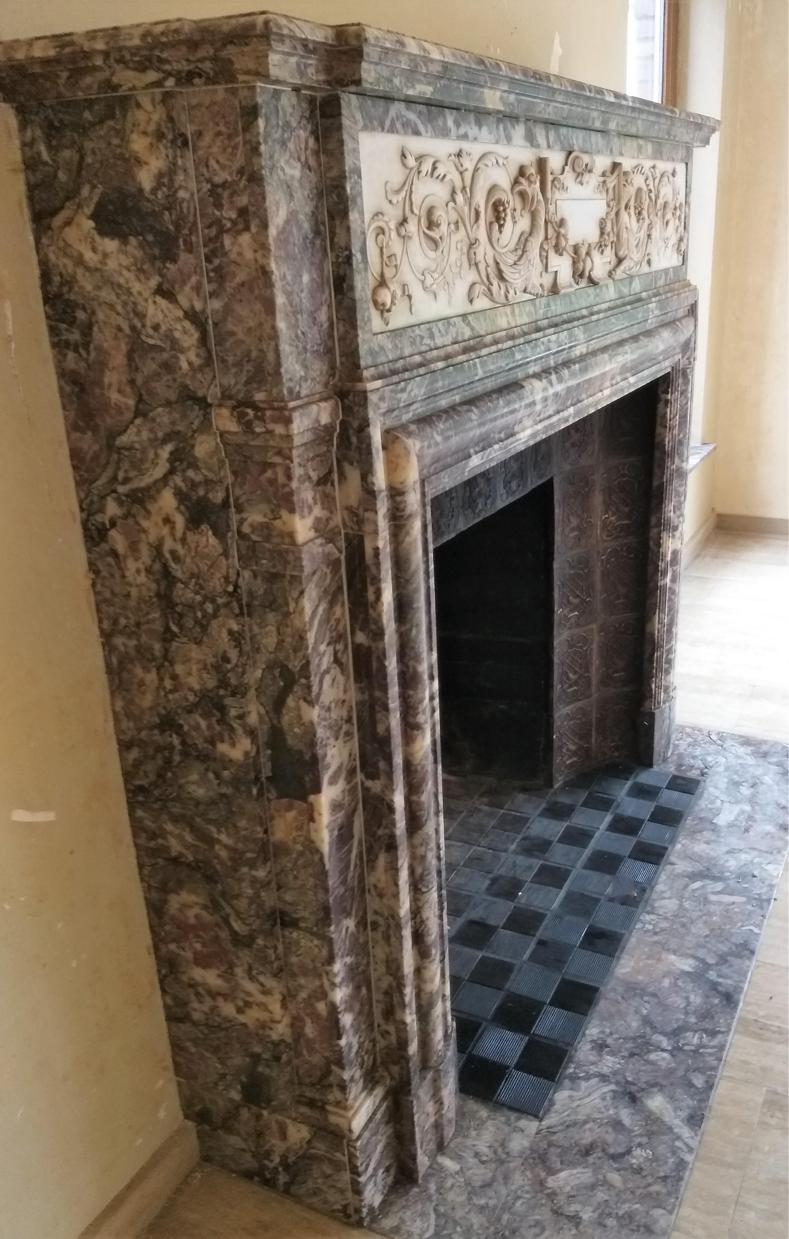 This big and exceptional fireplace was made in the mid of the 19th century of the highly valued Brèche Violet marble and Carrara Statuary marble, thus playins with the colors contrasts. The linteau in Carrara shows a cartouche in the center, flanked