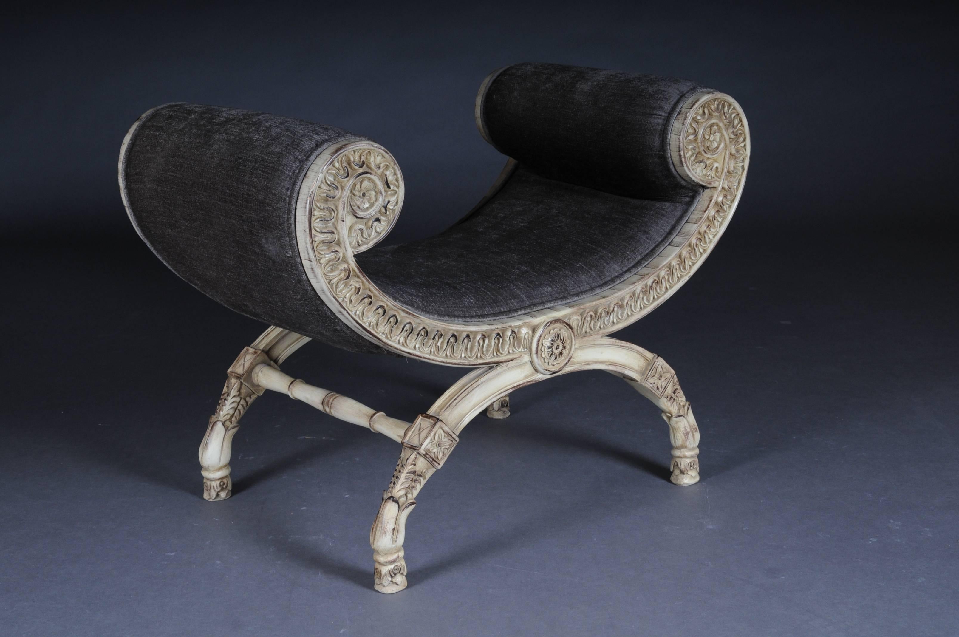 Solid beechwood, finely carved and set. Armrests ending in scrolled volutes. Semicircular frame on four scissor-shaped legs. Below connected by appropriately curly, strongly profiled webs. The seat is finished with a historical, Classic upholstery.