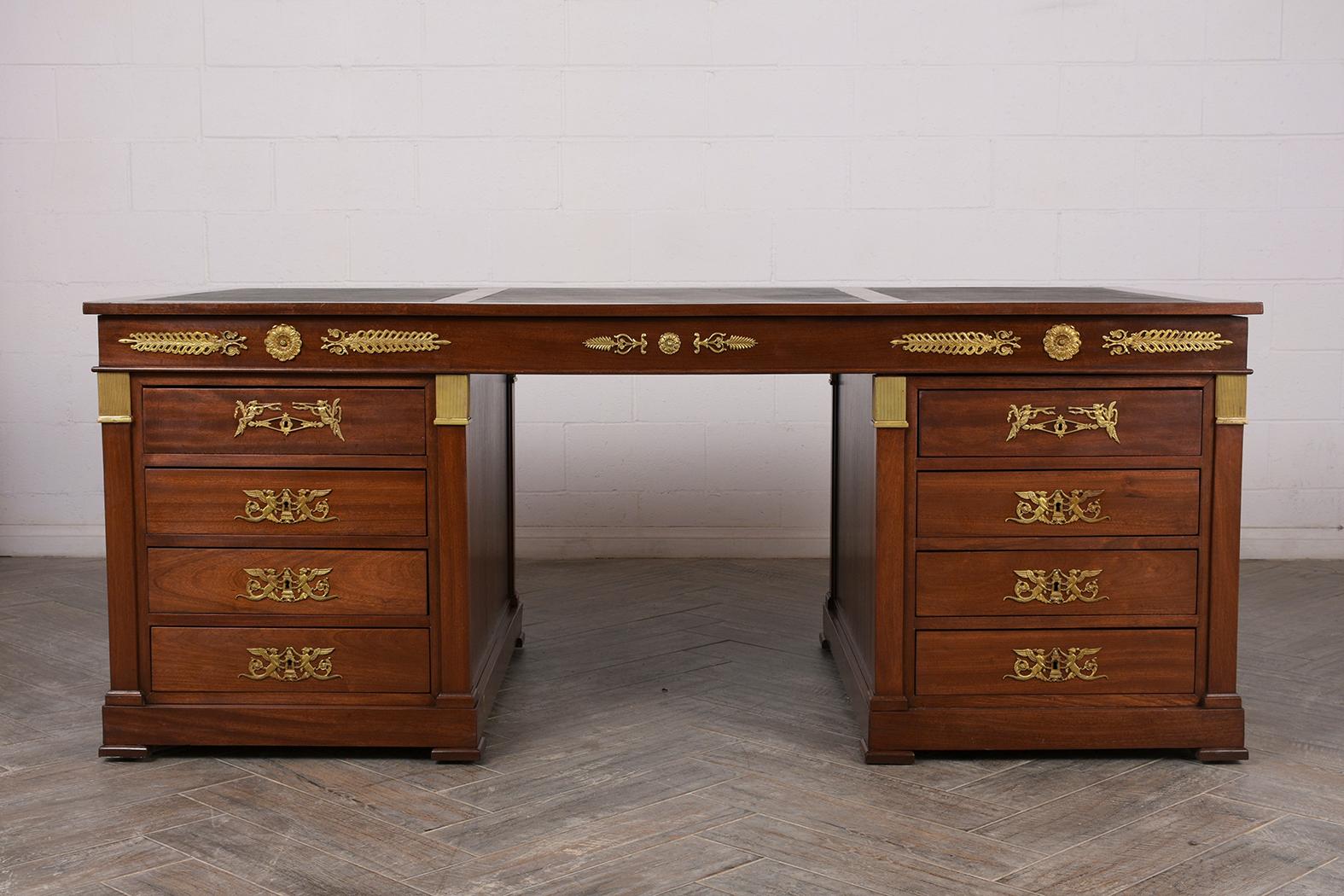 This French 1950s Empire-style Leather top desk double pedestal is made of mahogany wood stained a rich mahogany color with a satin lacquered finish. The desktop features excellent black leather inserts on the three sections, as well beautiful brass