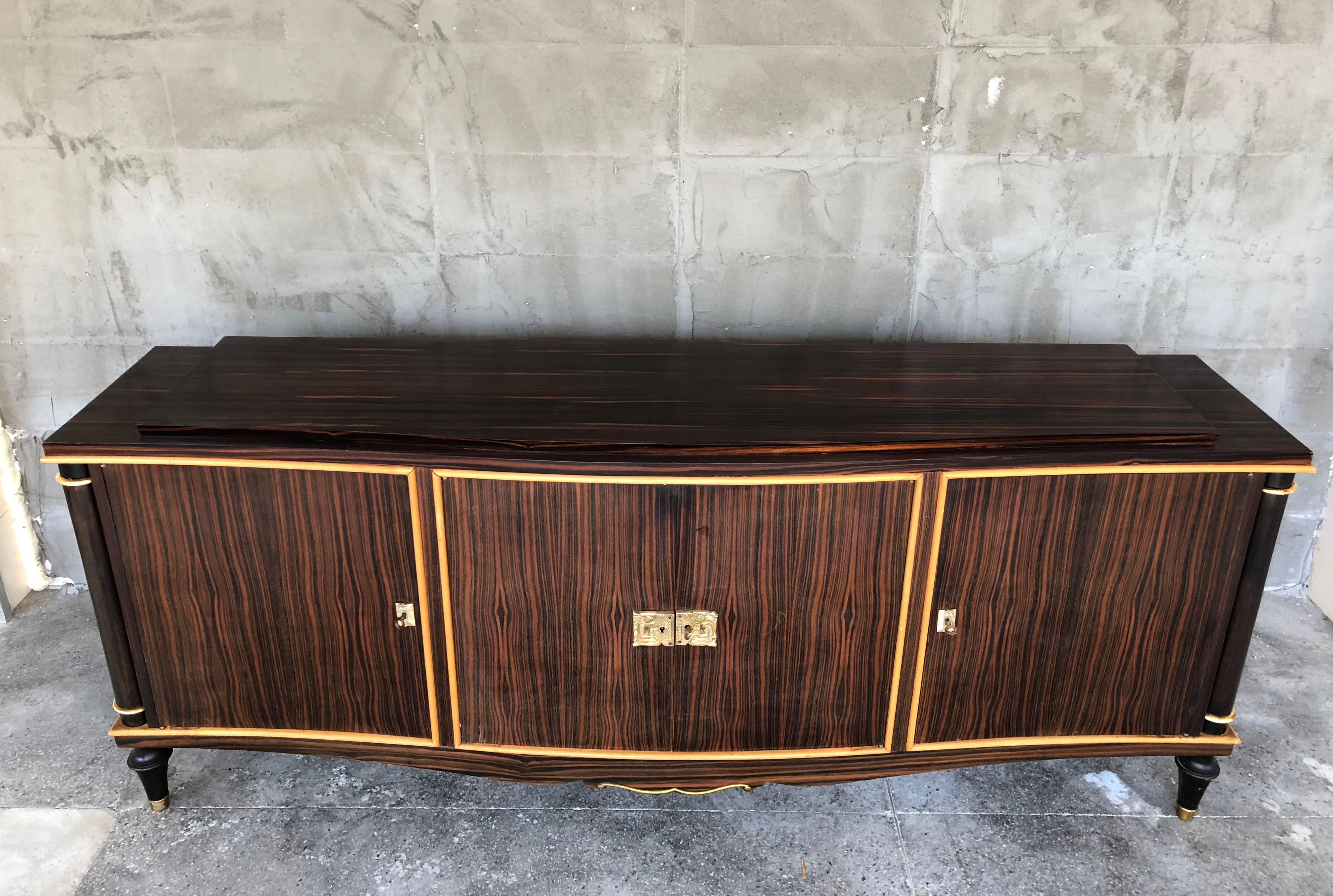 Important, really beautiful and classy Art Deco sideboard of Macassar ebony. He has it's company of same Macassar ebony table. Partially restored on the top and both sides. On the columns there are ring parties covered with gold leaf. Some of it has