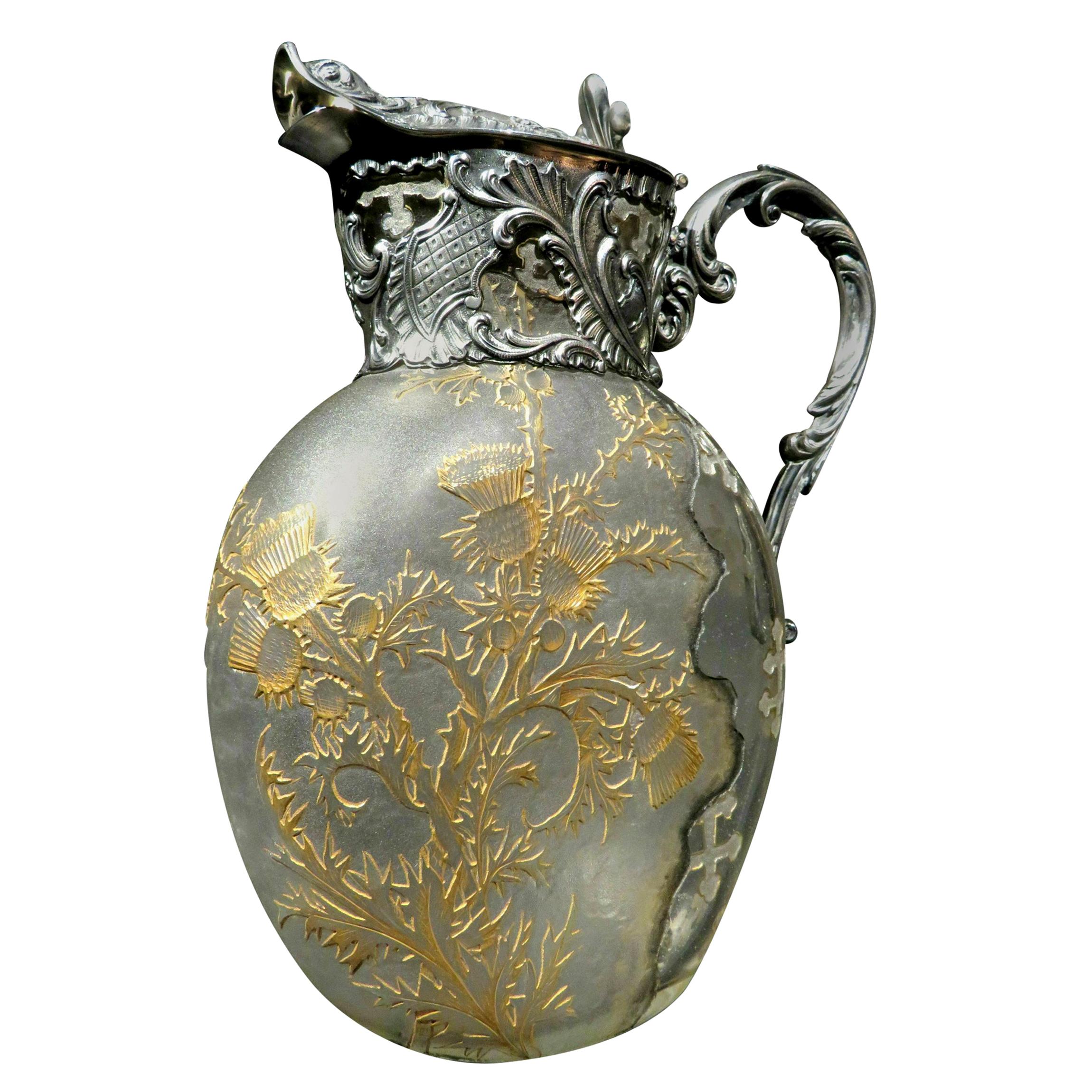 The flattened ovoid glass body having a partially textured surface decorated with etched thistle motifs highlighted in gilt detail, the remaining clear area decorated with textured motifs of the cross of Lorraine outlined in gilt. The neck fitted