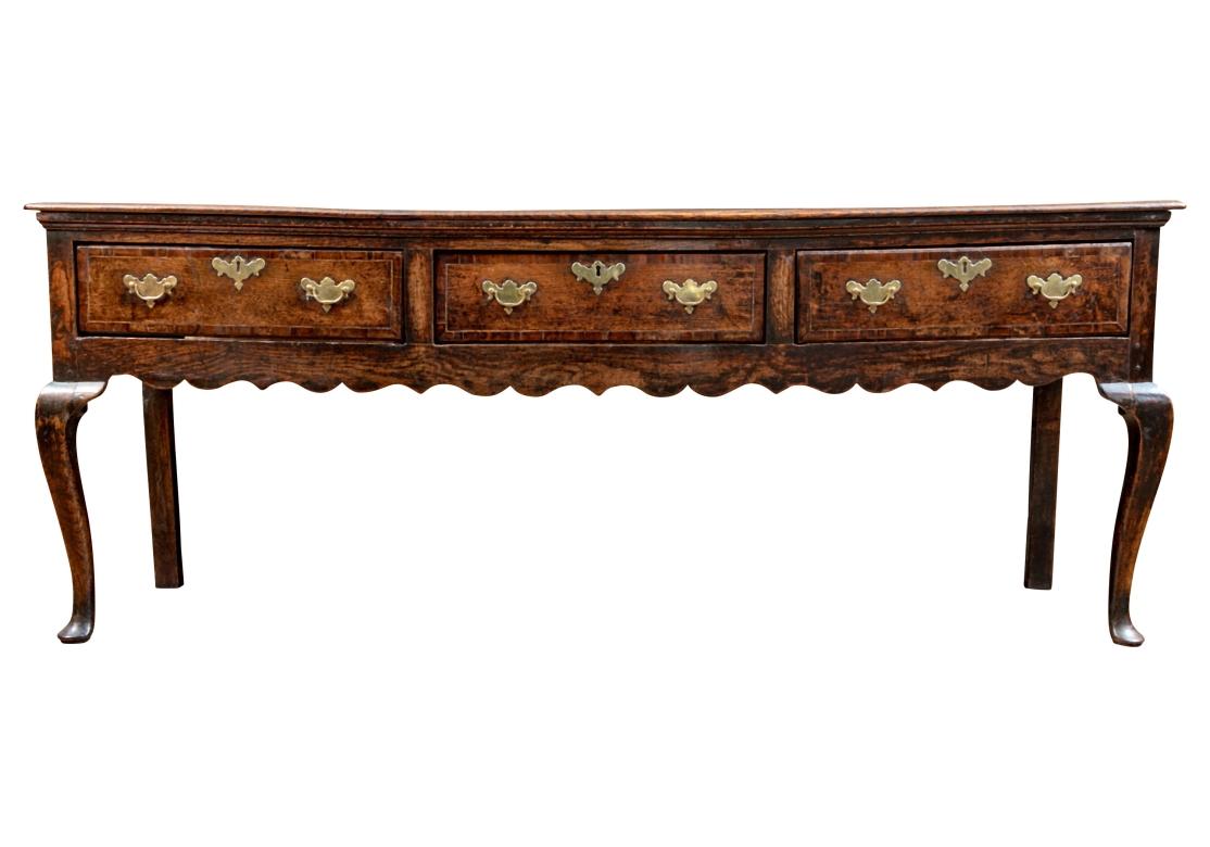 A fine 18th Century Oak Hunt Board in Classic Welsh style and form. The Hunt Board a two-plank top with back gallery,  carved apron, three banded drawers with dove-tail joinery, strongly carved Cabriolet front legs and later brass Bat Wing pulls and