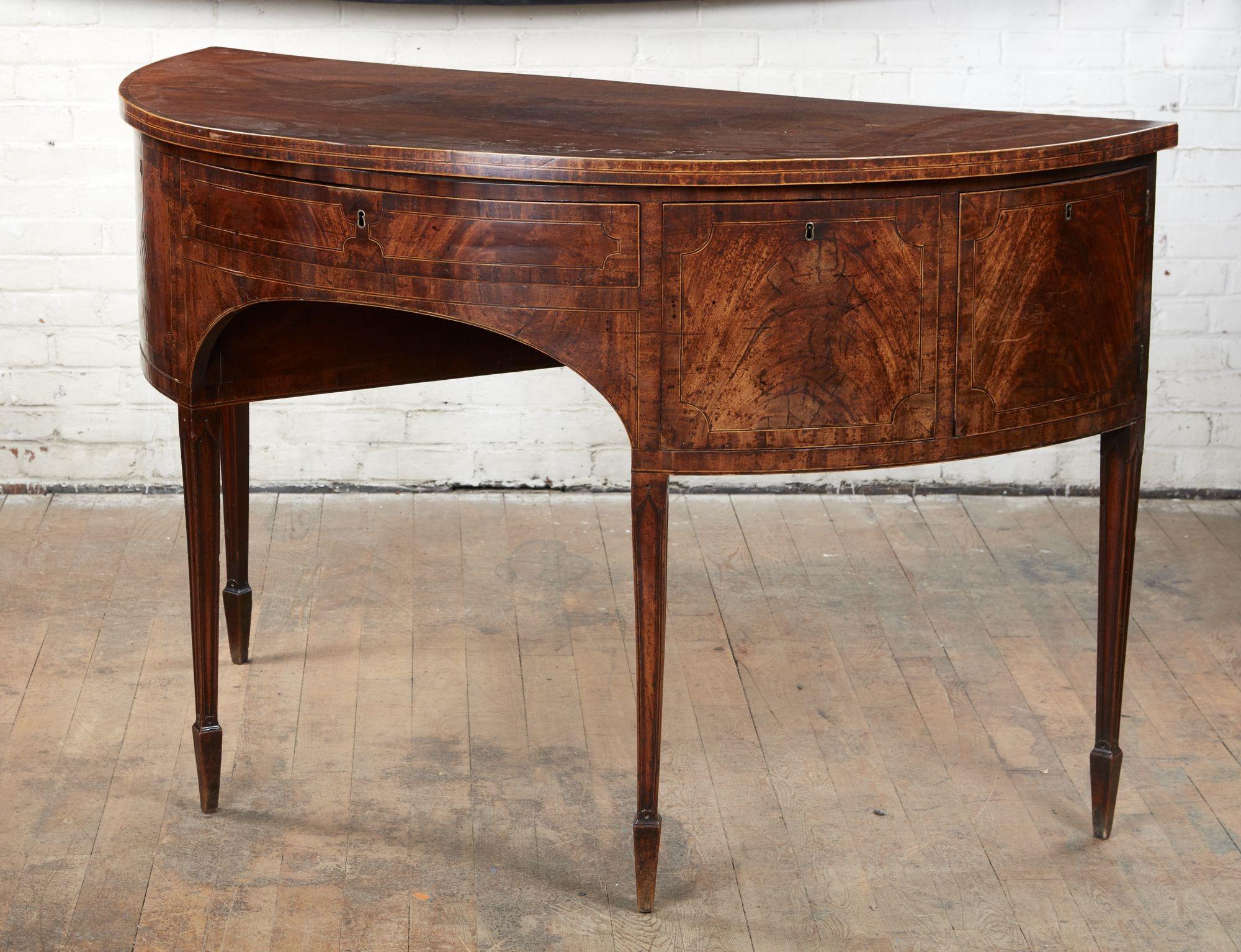 Exceptionally fine George III mahogany demilune sideboard, the richly figured and patinated single board top with holly stringing and mahogany crossbanding, the shallow middle drawer with fitted compartment and flanked by fitted drawers and drawers,