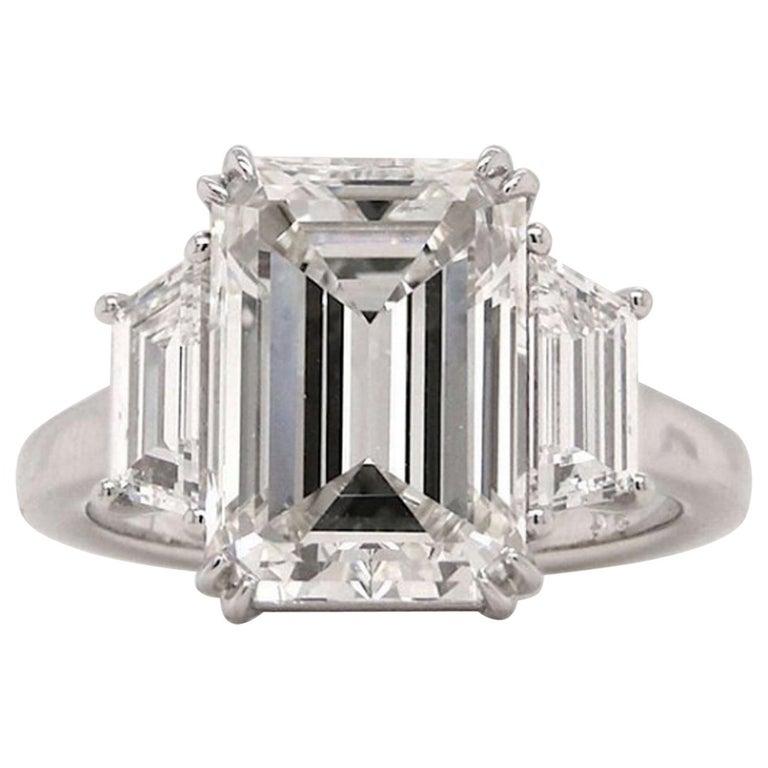 This elegant ring features a stunning 4.01 carat emerald cut diamond as its centerpiece, set in a timeless platinum band. 

The central diamond has a color grade of G, offering a bright and near-colorless appearance that enhances its natural