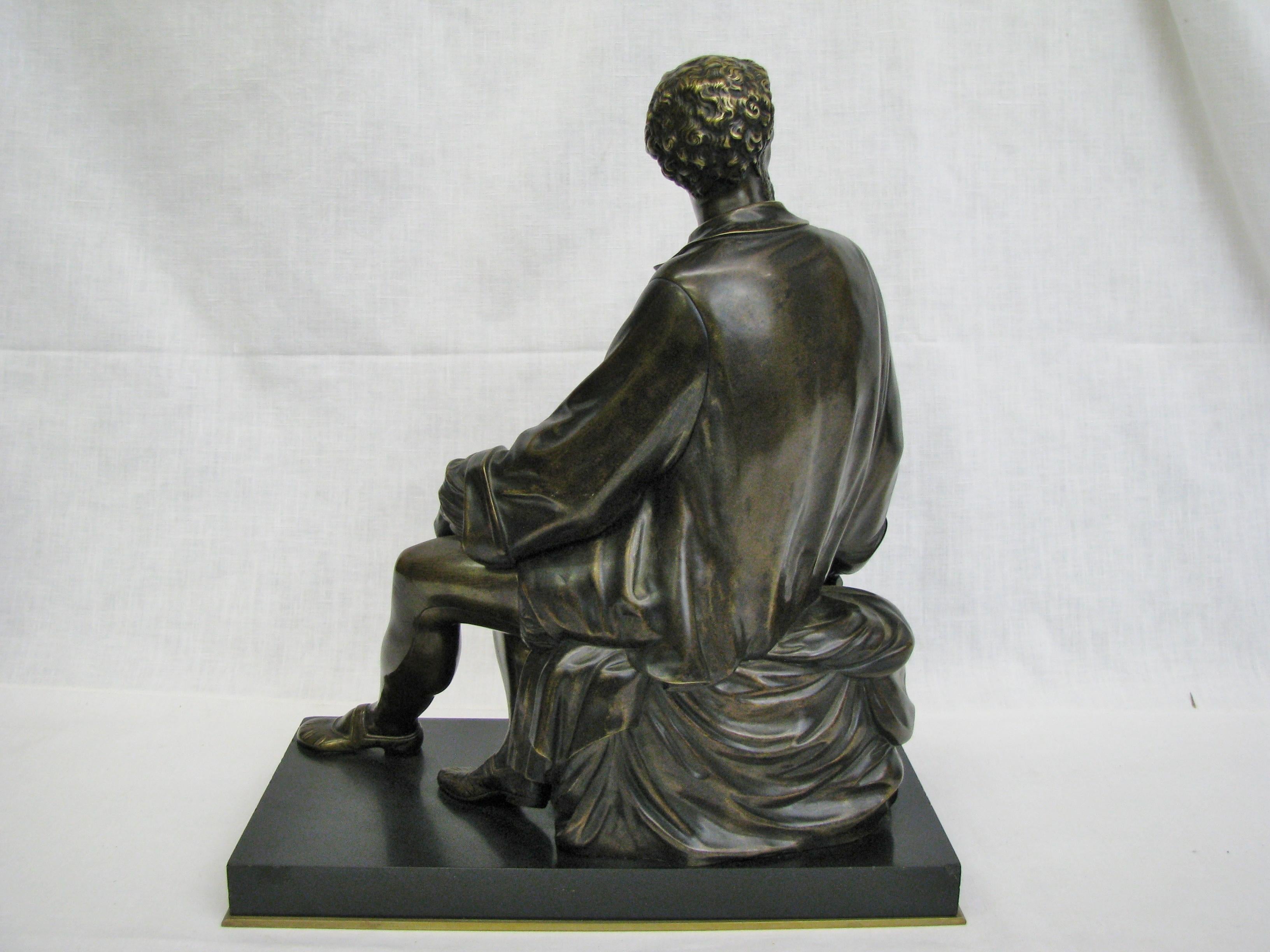 Beautifully modeled late 19th century cast bronze figure of a seated sculptor in Renaissance dress. Holding a hammer in his right hand and his chisel in his left. A sample of his work, an oval cartouche featuring putti rests at his side. Wonderfully