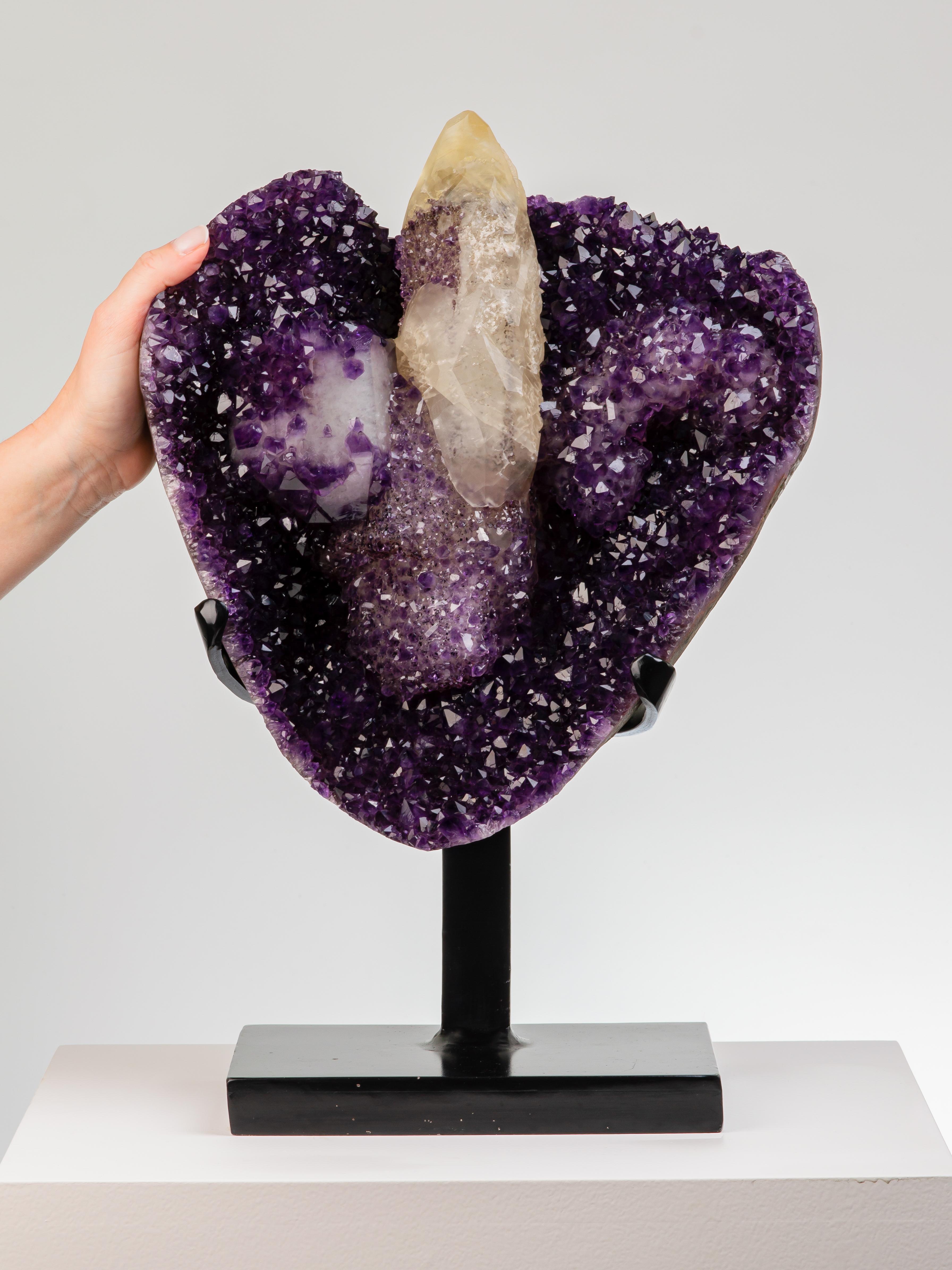 A stunning heart-shaped amethyst formation with a central rocket-shaped
calcite covered with a blanket of amethystine quartz and black goethite.
To the left an icy calcite covered in deep amethyst crystals.

This piece was legally and ethically