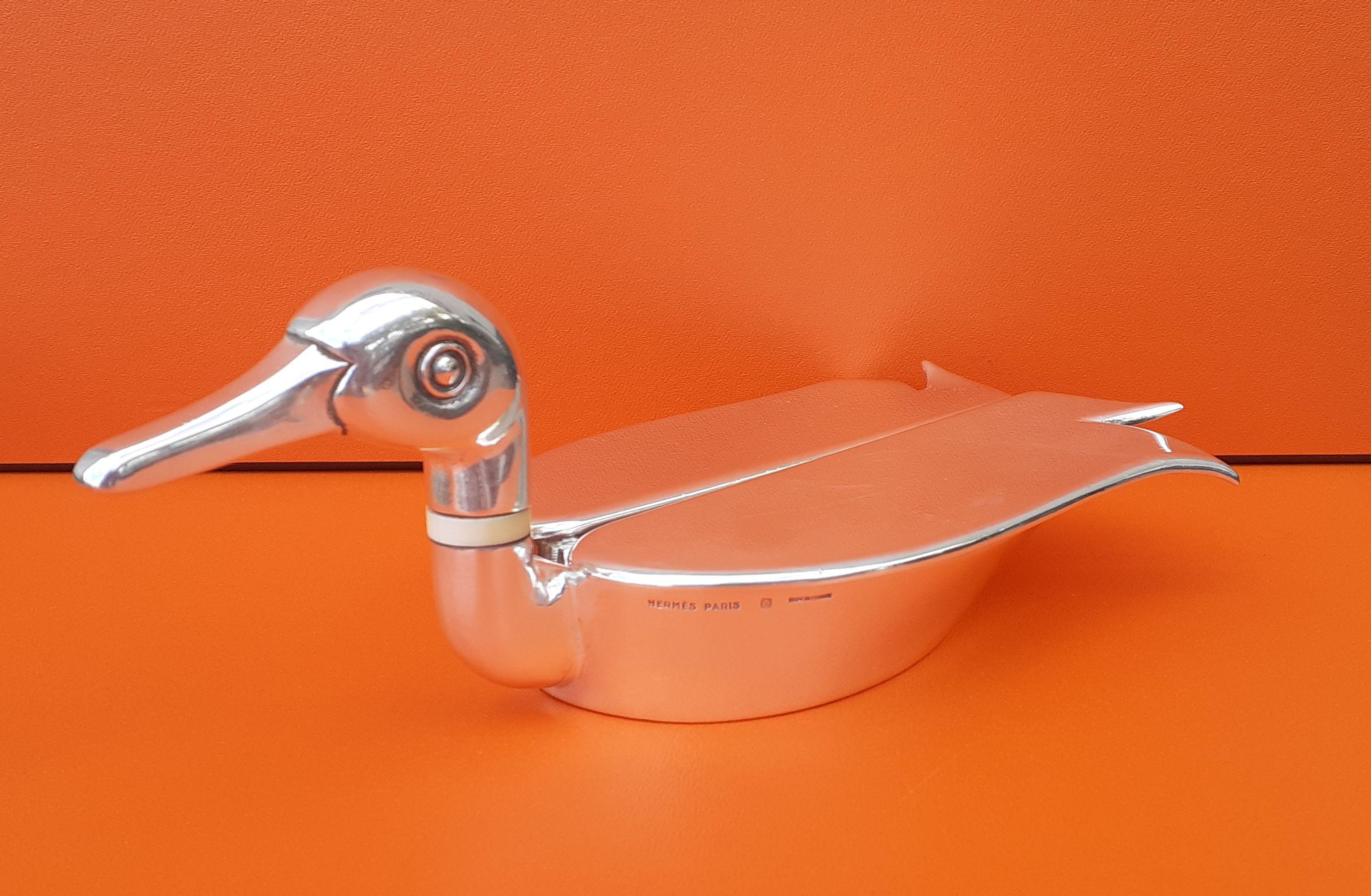 Rare Authentic Hermès Change Tray

In shape of a Duck

Can be used as ashtray

Made in France 

Vintage item

Made of silver-tone metal (non precious)

The 2 wings open and reveal a change tray. Can also be used as an ashtray

