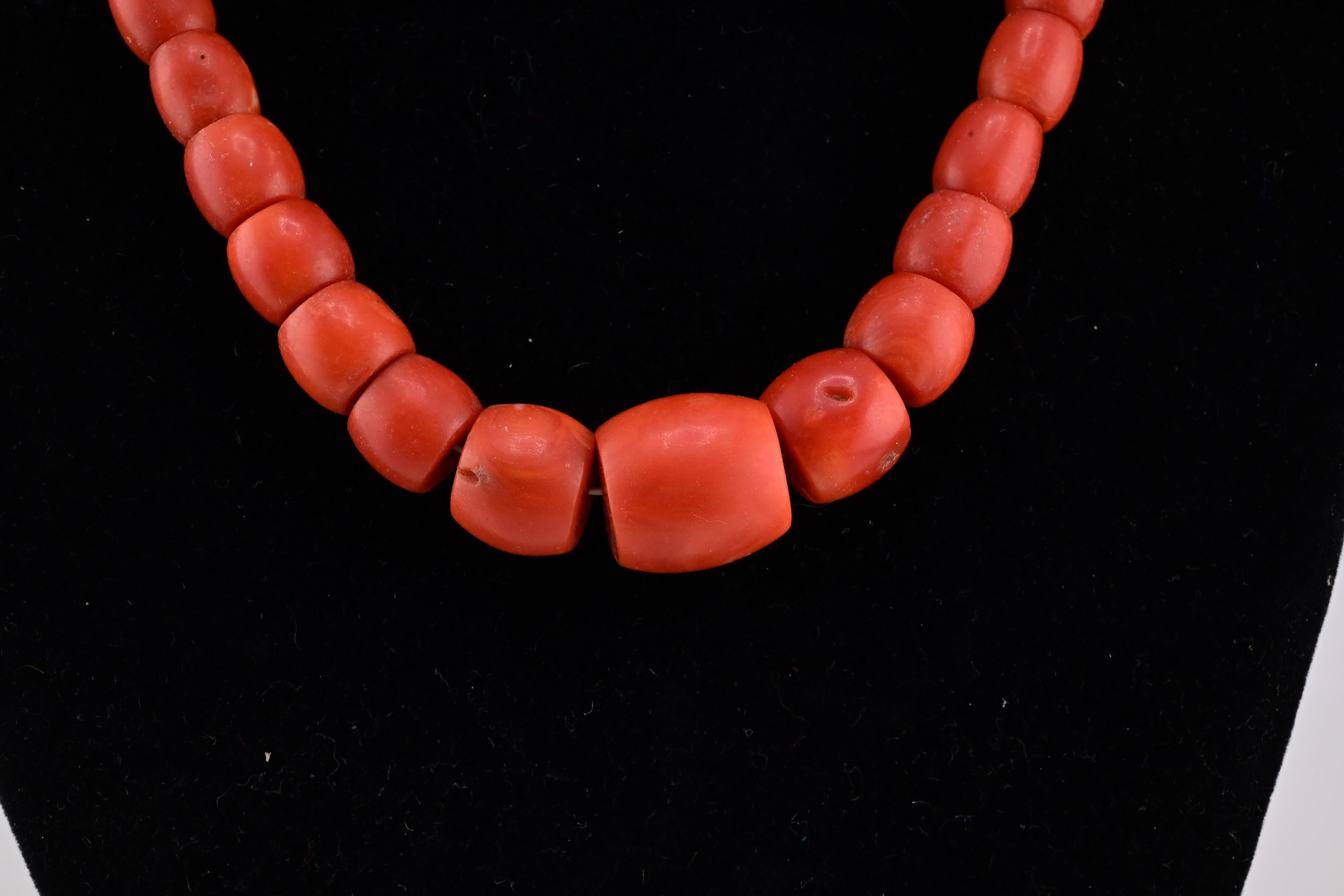 A striking necklace featuring a series of smooth, rounded barrel coral beads.

The beads display a rich, vibrant red color, each varying slightly in size and shape, adding a natural and organic feel.

They are strung together seamlessly, creating a