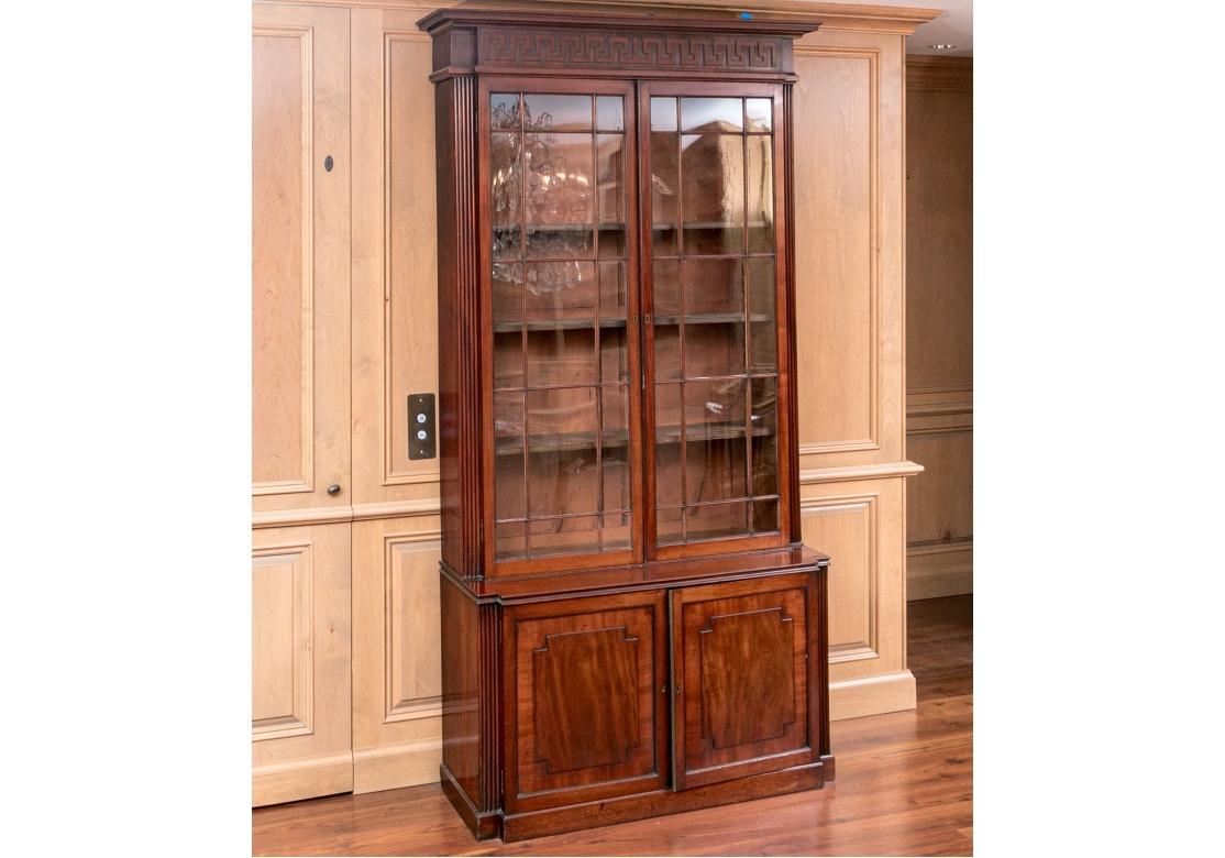 An elegant Antique Cabinet with fine form and having a trim side profile. A tall Antique Bookcase cabinet in two parts with fine details including glass paned doors with fret work,  interior shelving, fluted corners, decorative raised door panels