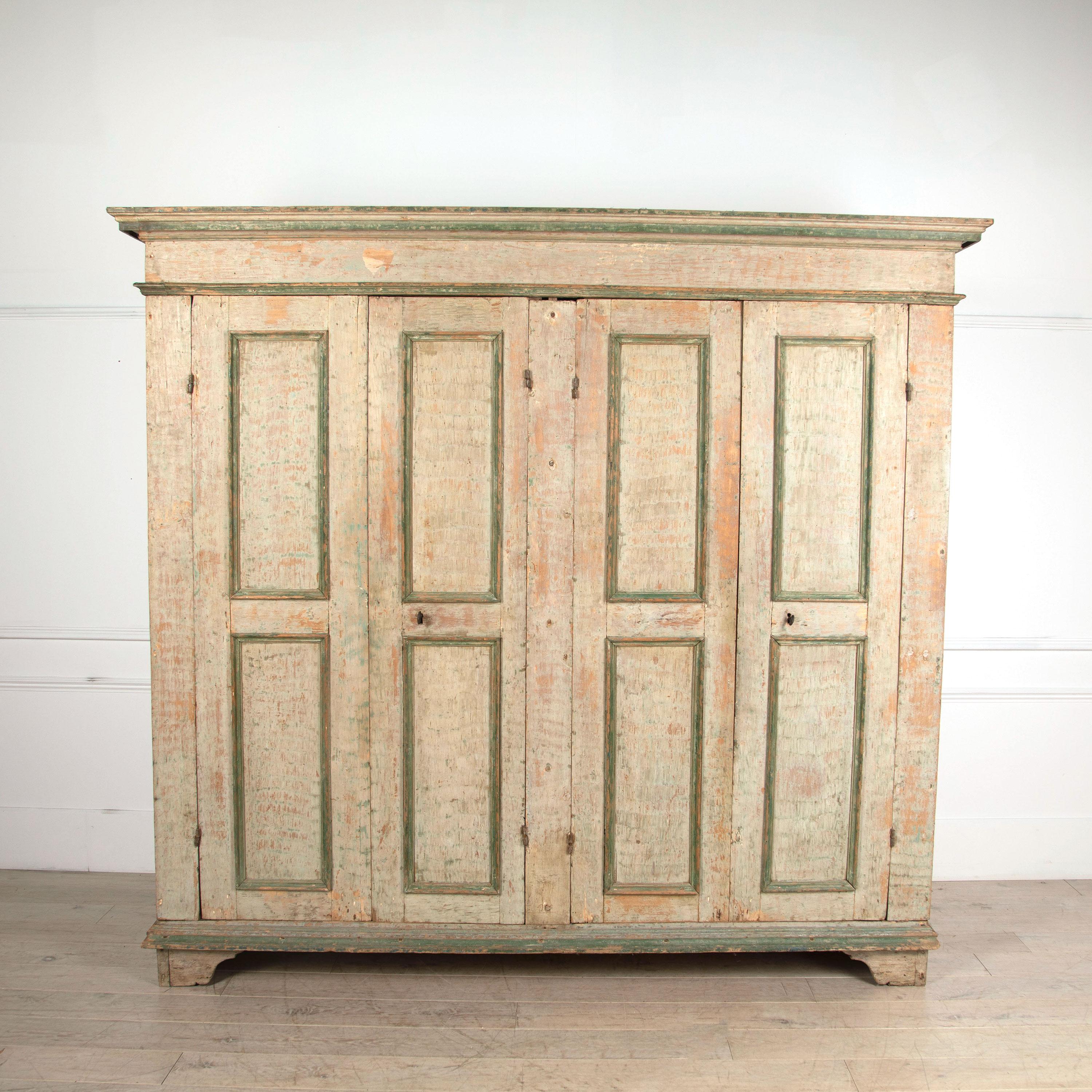 An exceptional Italian four-door cupboard scraped to reveal original paint layers. The piece is in wonderfully original condition with minor losses to the moulding, circa 1800.