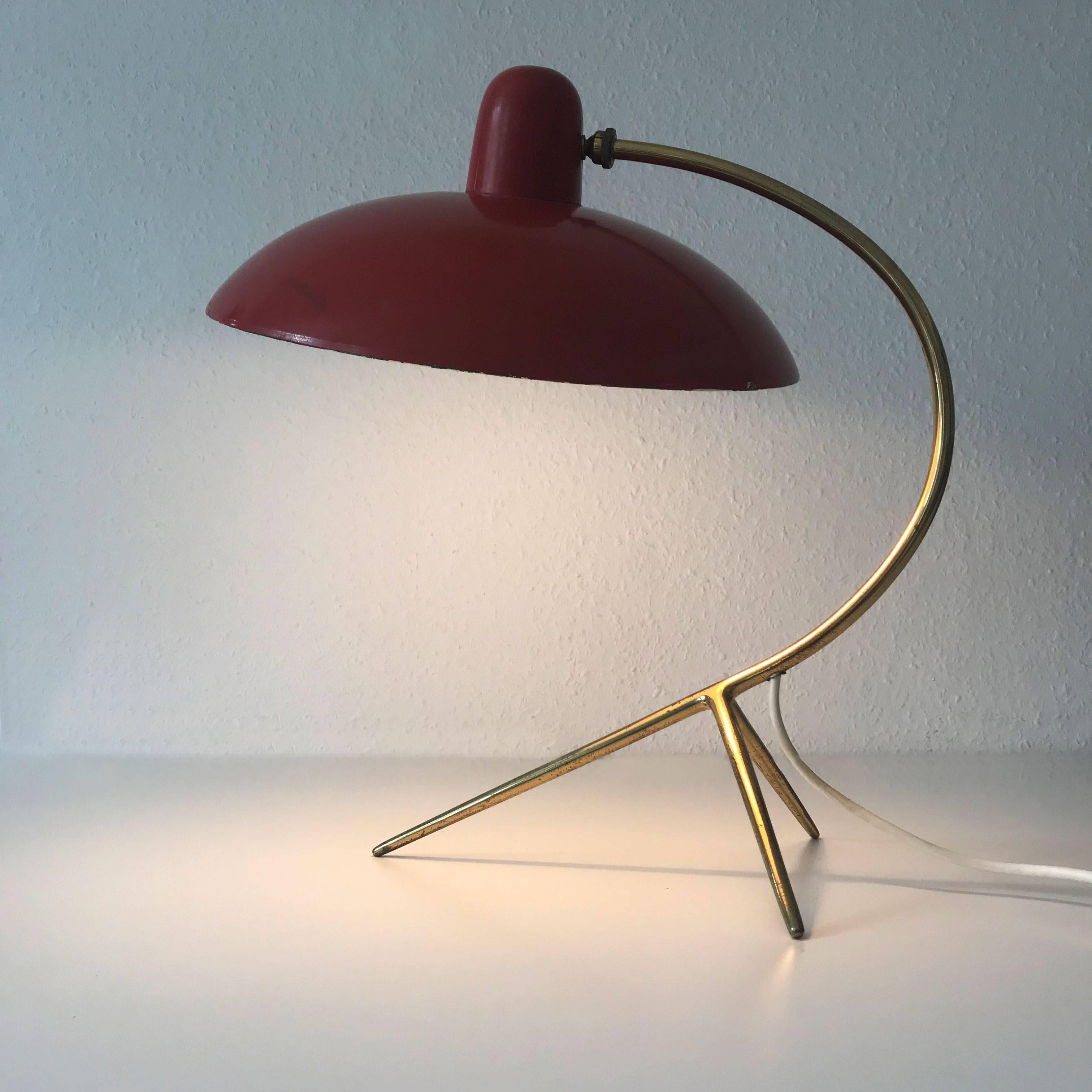 Gorgeous, large Mid-Century Modern table lamp in a rare tomato red color. Designed and manufactured in 1950s, Italy.
This elegant table lamp is executed in brass and tomato red lacquered metal lamp shade.
It is executed with a E27 screw fit bulb