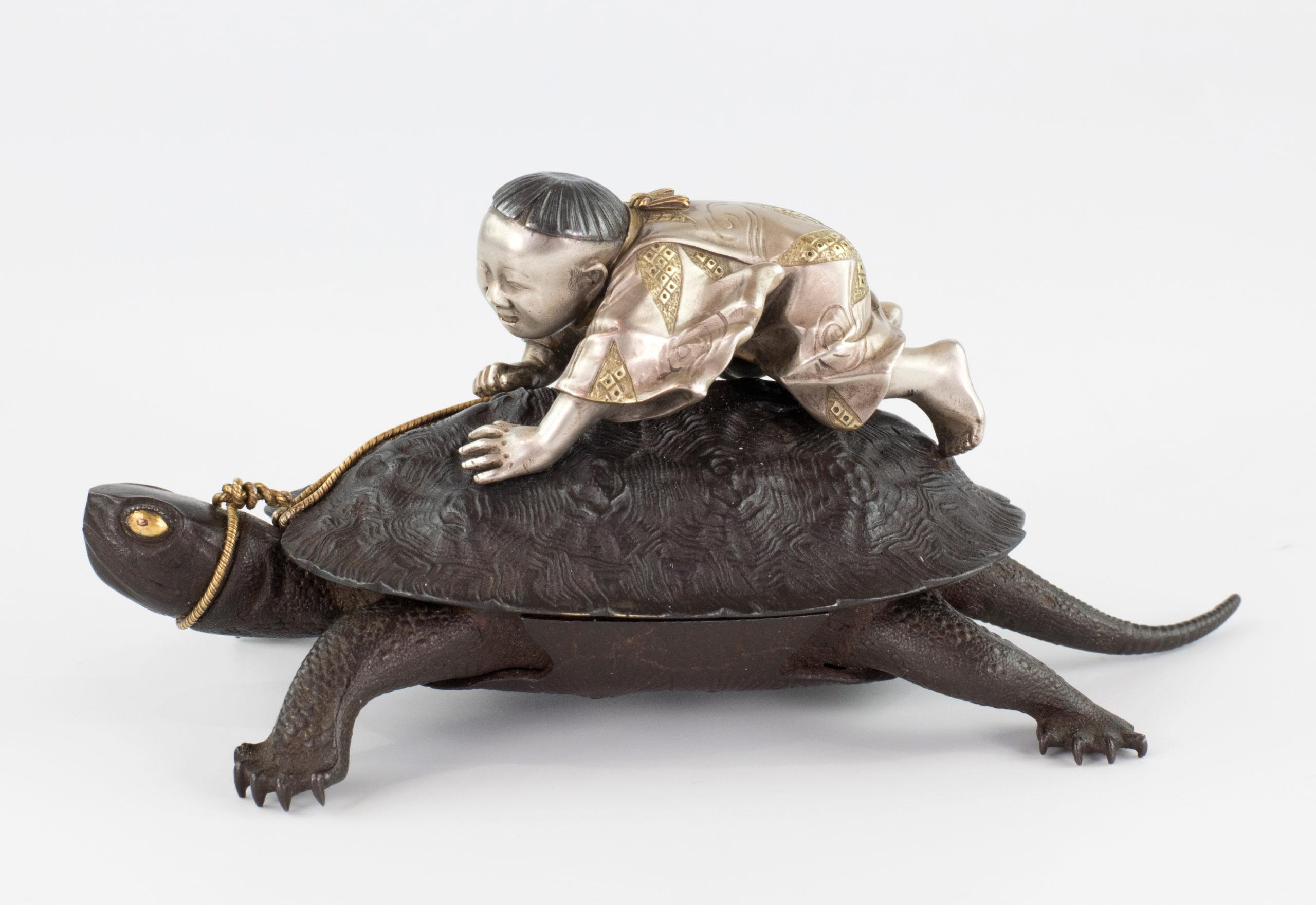 As part of our Japanese works of art collection we are delighted to offer this captivating Meiji Period 1868-1912, iron and mixed metal study of a turtle being ridden by a young boy, the boy is full of glee as he clutches onto a gold coloured rope