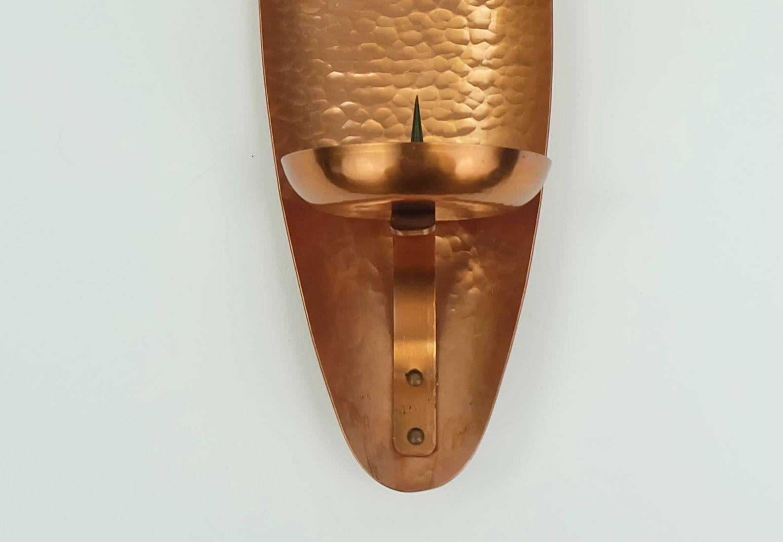 Sehr dekorativer Wandleuchter aus den 1950er/60er Jahren. Hergestellt aus gehämmertem Kupfer. Für eine runde oder gerade Kerze. Auf der Rückseite steht Wall Handcrafted Made in Germany. 

Abmessungen in cm:
Länge 40 cm, Breite 11 cm, Tiefe 11 cm,