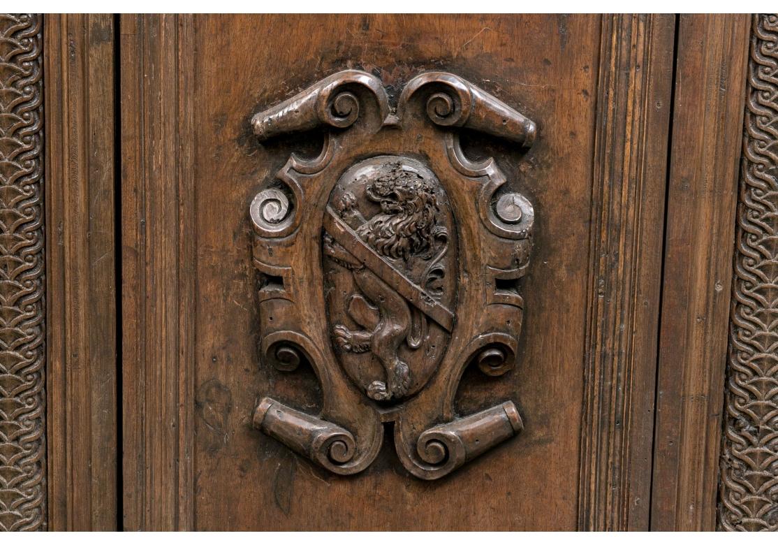 Ein außergewöhnlicher antiker Schrank im Renaissancestil mit imposantem Stil und Präsenz. Massiver Schrank mit einer zentralen Tür mit geschnitztem Wappenelement, flankiert von zwei Türen mit geschnitzten Blumen und kannelierten Holzgriffen. Die