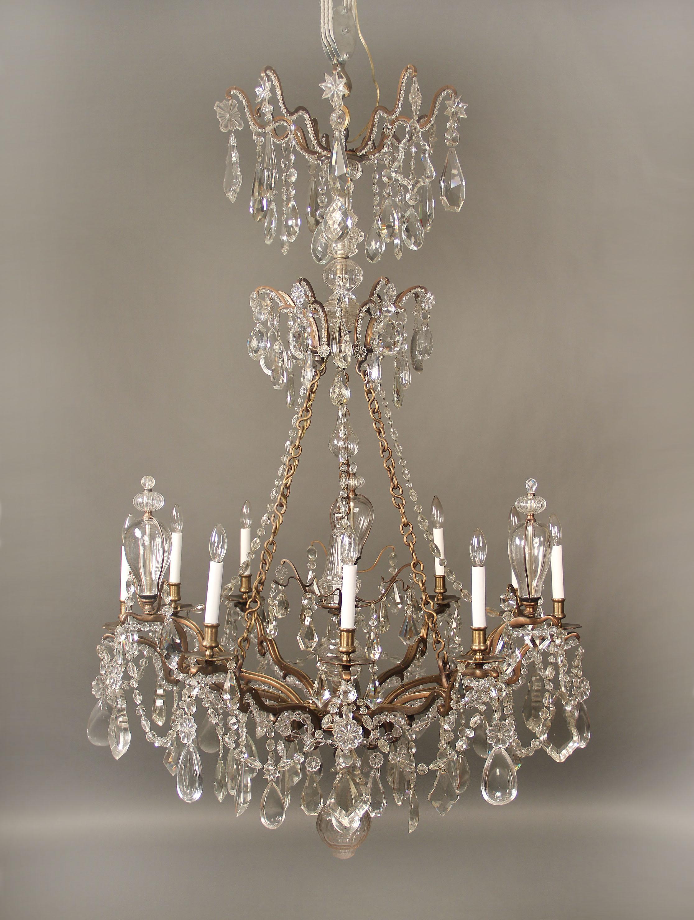 An exceptional late 19th century bronze and crystal ten-light chandelier

Multi-faceted and shaped crystal including half pear designs, three bottles and a central finial, cut crystal central column with beaded arms, one interior and nine
