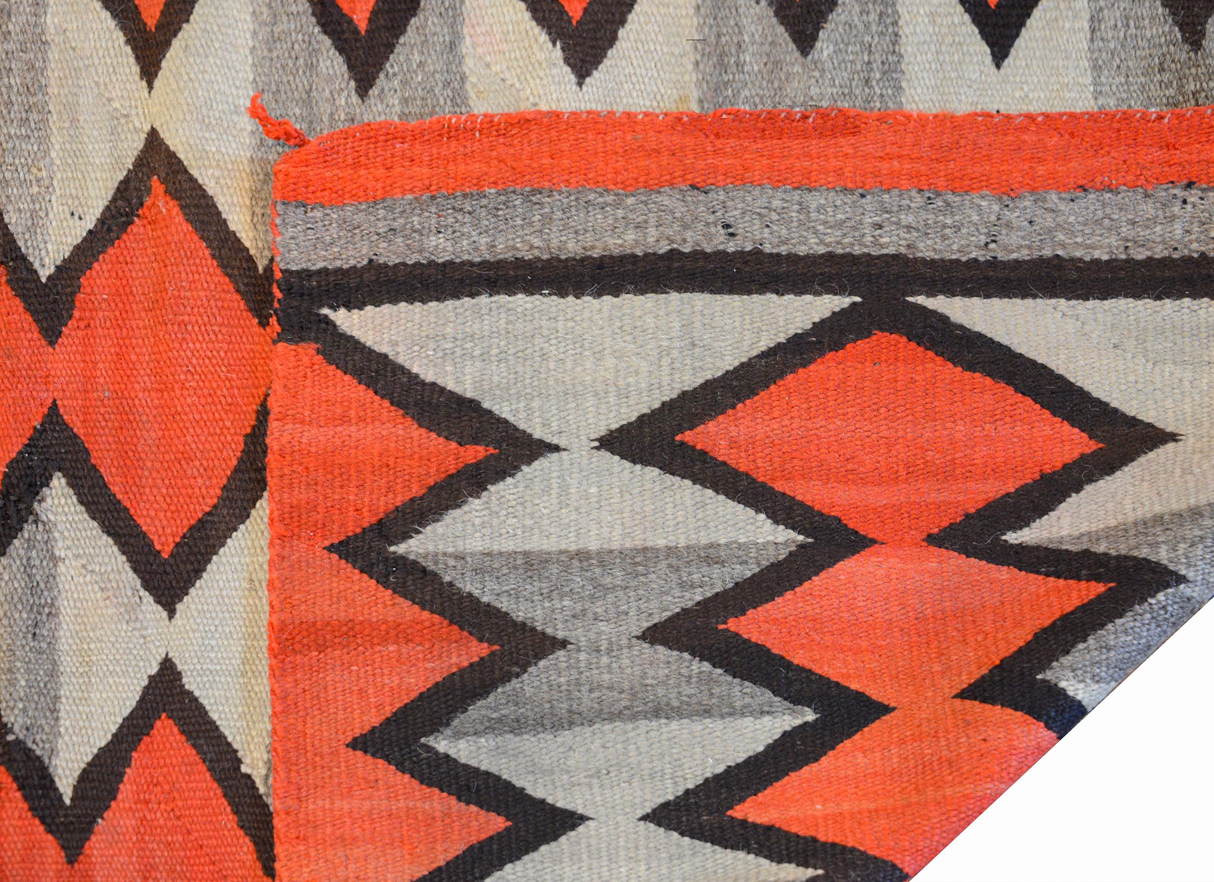 An exceptional early 20th century Navajo rug with a two grey striped background overlaid with several abrash crimson zigzag stripes flanked by thick black stripes. The ends are striped with crimson, grey, and black.