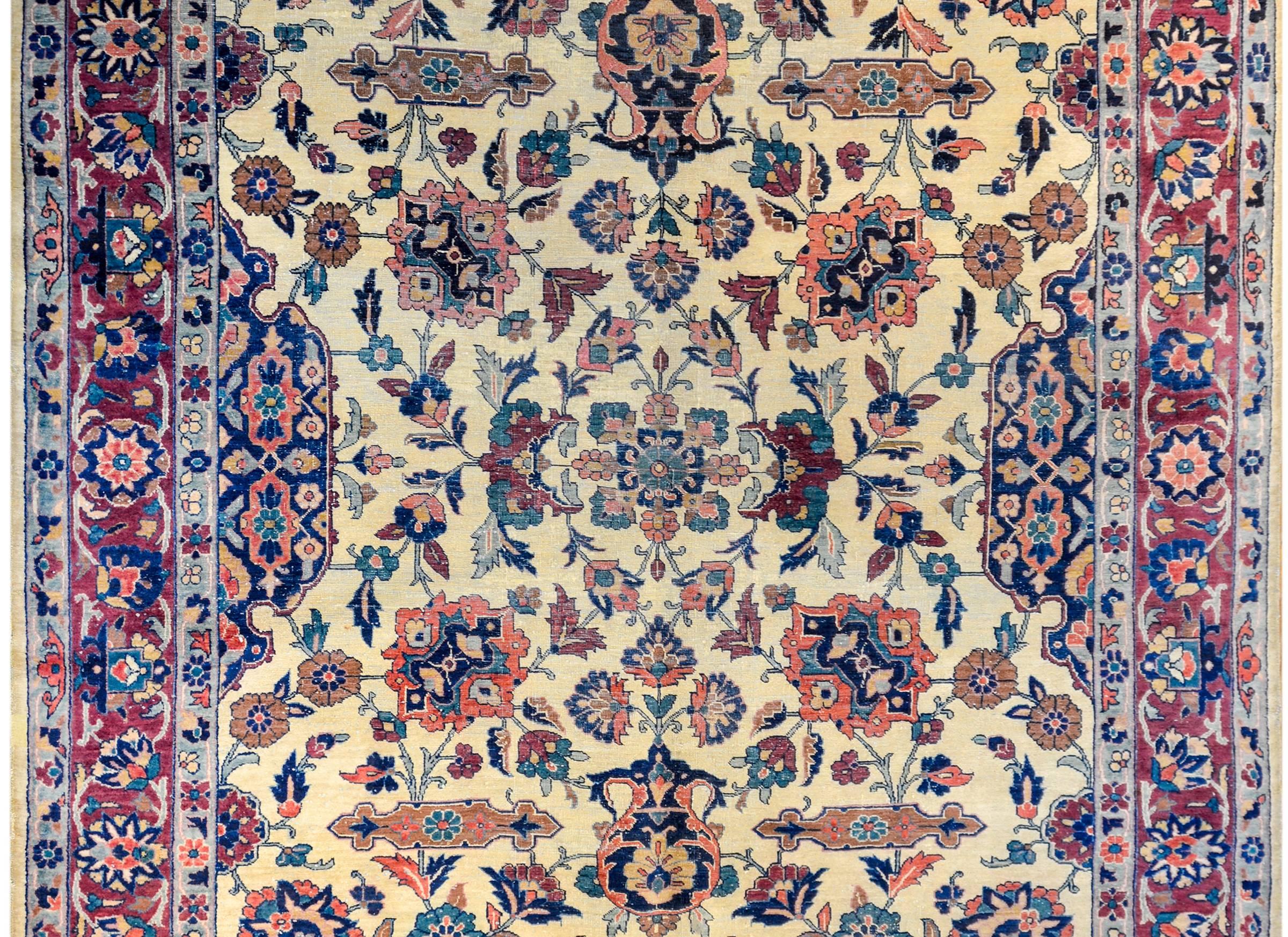 An exceptional late 19th century Persian Sarouk Mohajeran rug with a beautiful mirrored finely woven field of myriad flowers and vines woven in indigo, pink green, and crimson, on a pale yellow vegetable dyed wool background. The border is