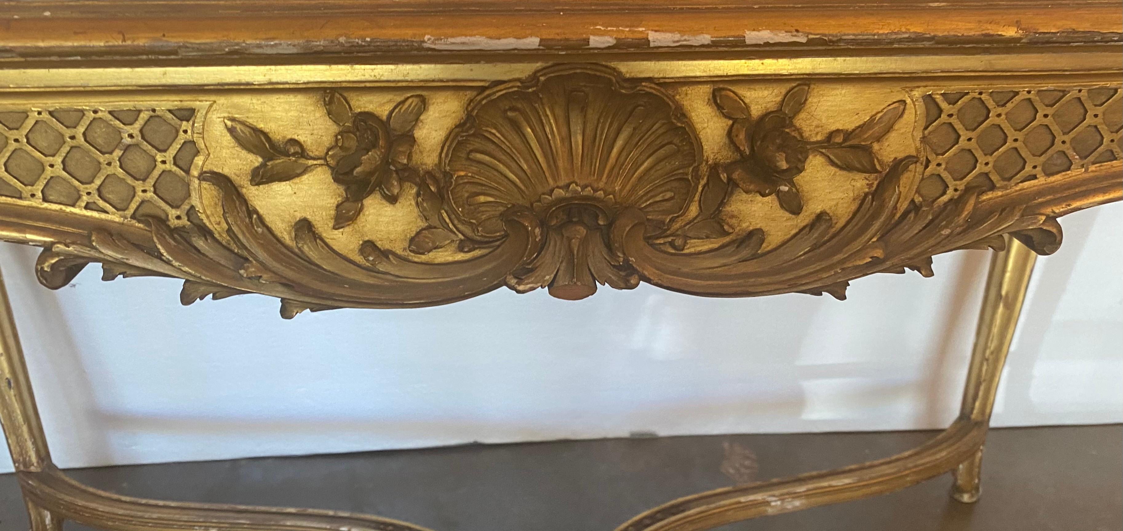 Excepcional mesa dorada con tablero de mármol de estilo Luis XV, mediados del siglo XIX, con tablero de mármol en forma de inserto, sobre delantal tallado con motivos foliados y de conchas, que se eleva sobre patas cabriolé, unidas por una cruceta